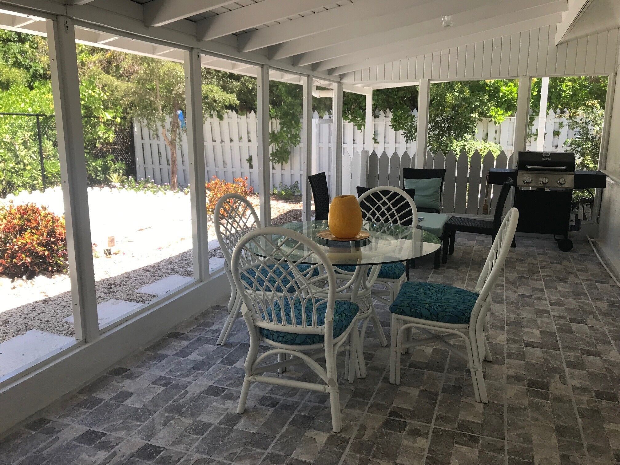 The screened porch with a round glass table and chairs.