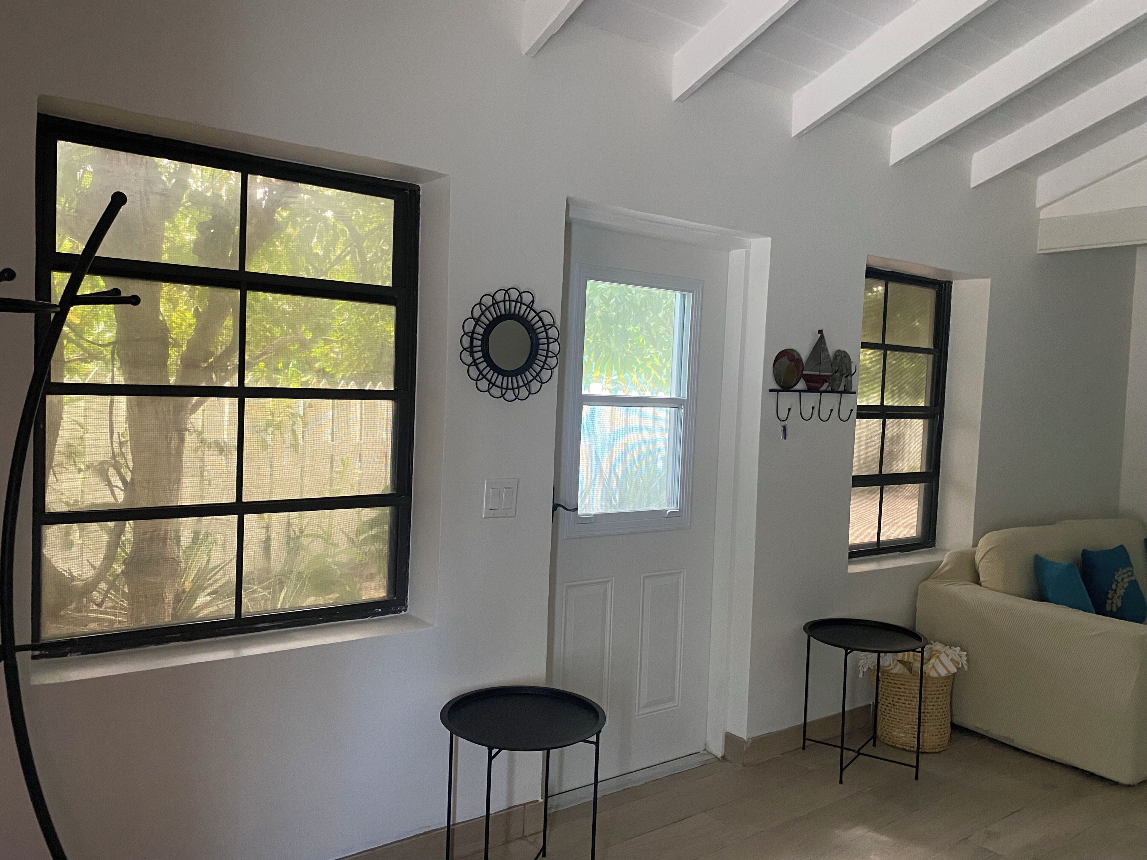A room with a white door, two side tables, and a sofa.