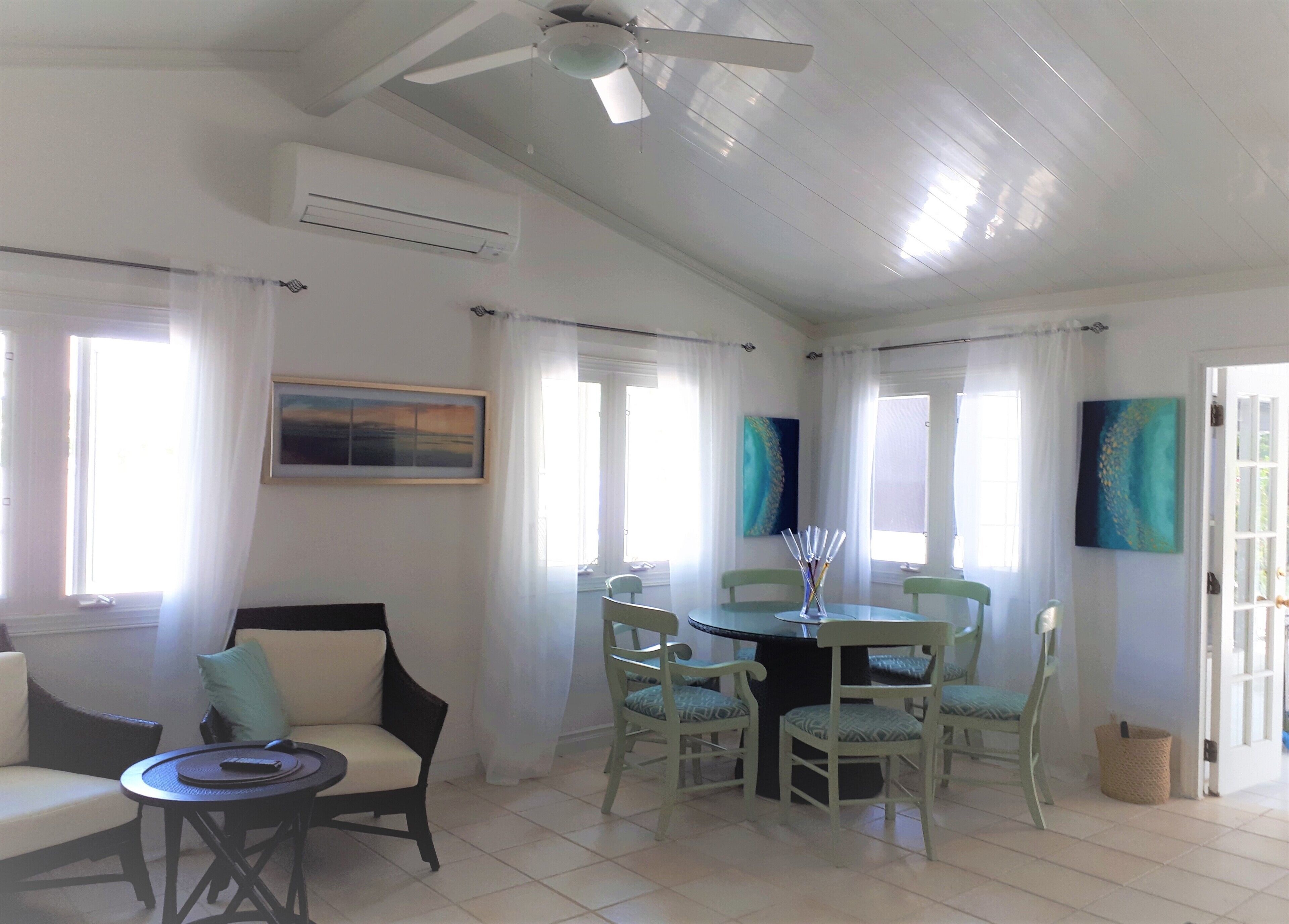 The dining area with a round table and green chairs.