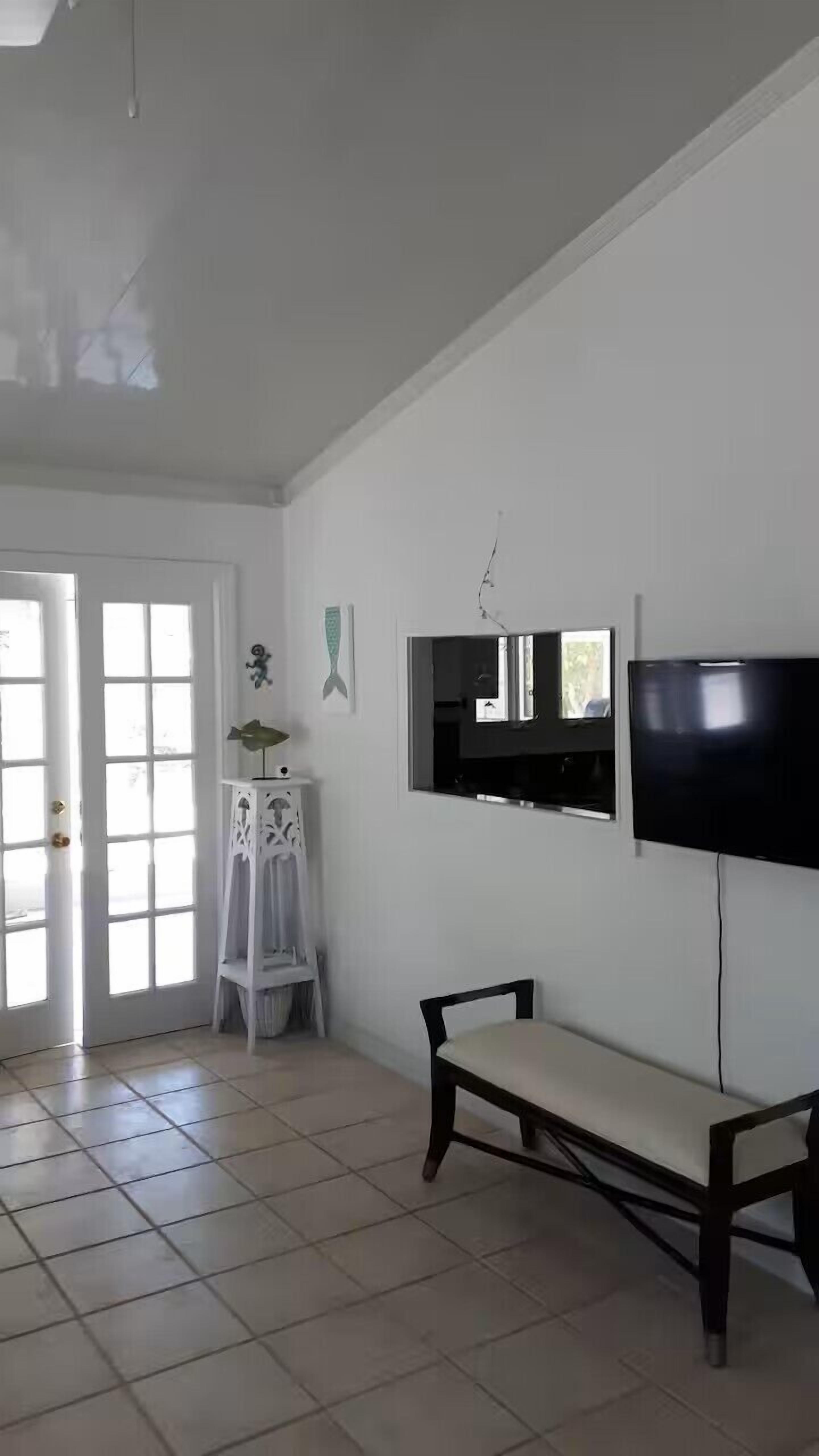 A room with french doors, a bench, and a wall television.