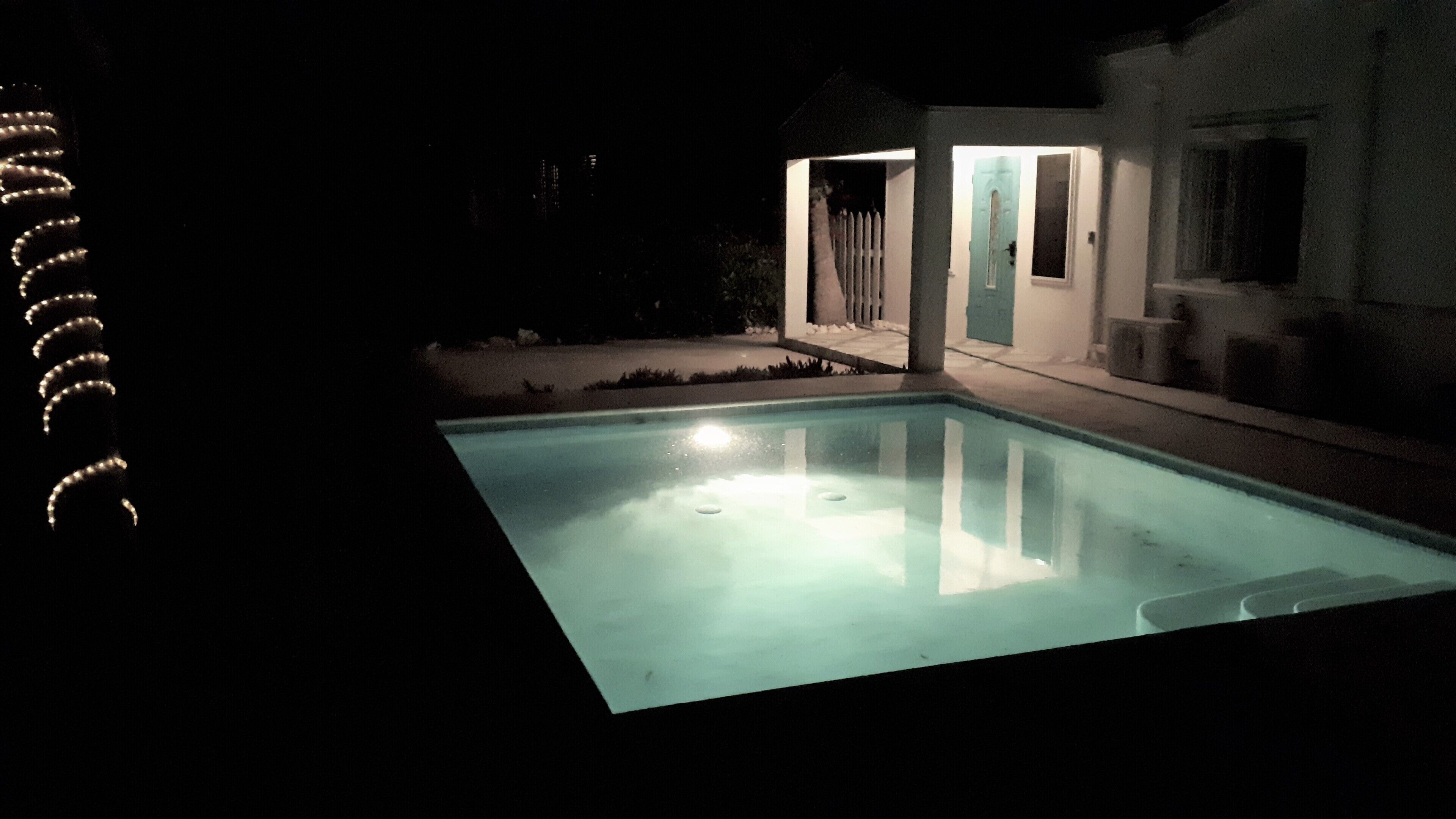 The pool at night with the lighted porch behind it.