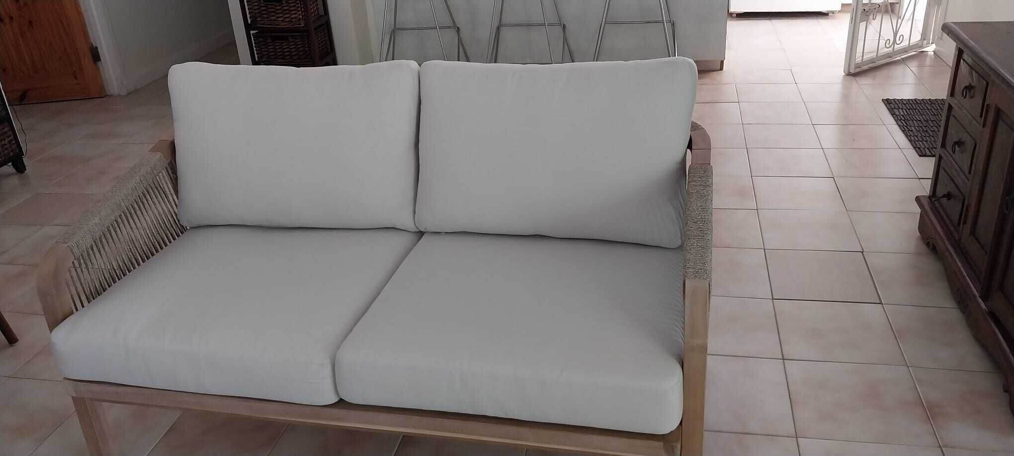 A two-seat sofa with a wood frame and white cushions.