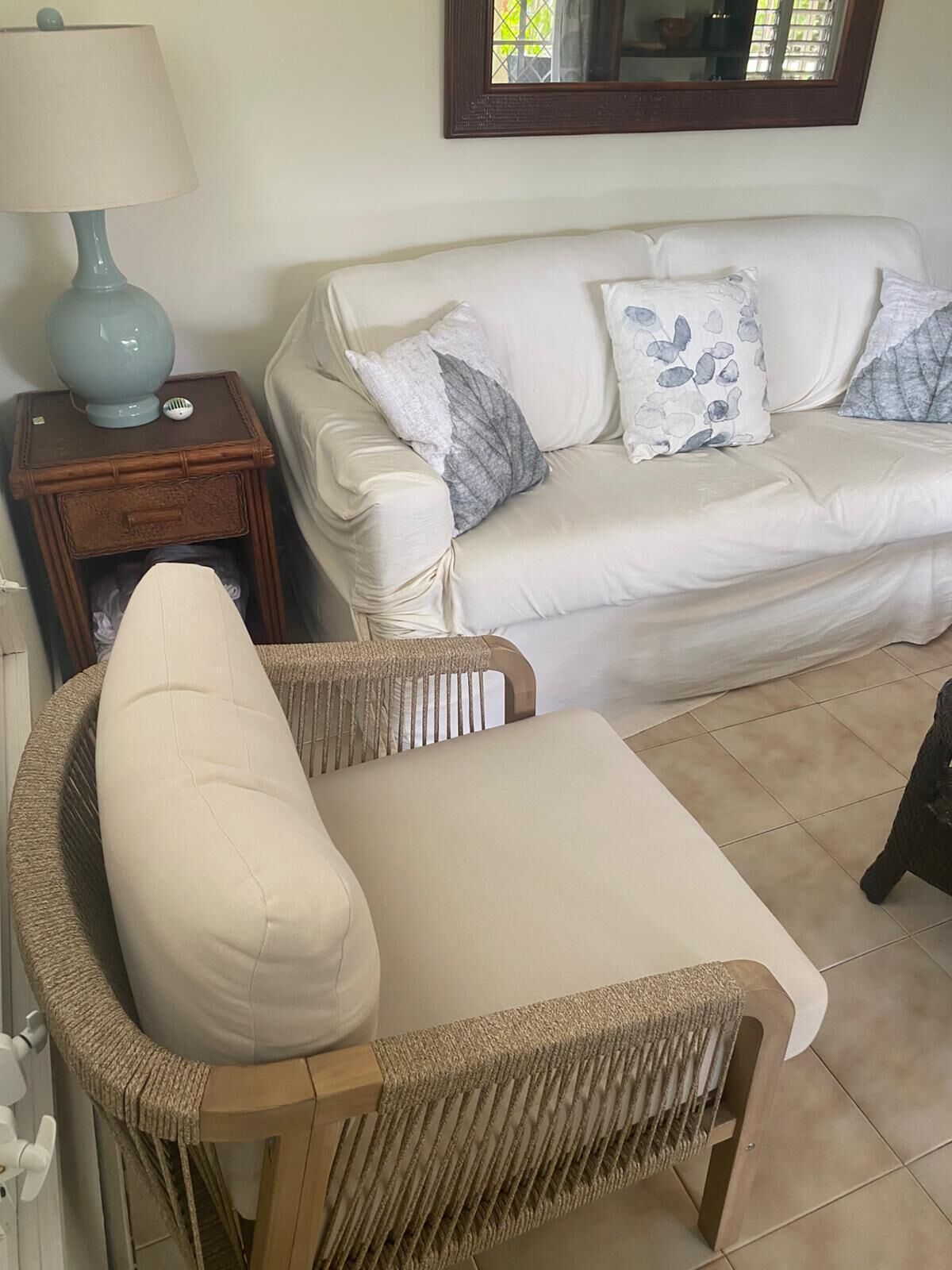 A white sofa with leaf-print cushions next to a side table.