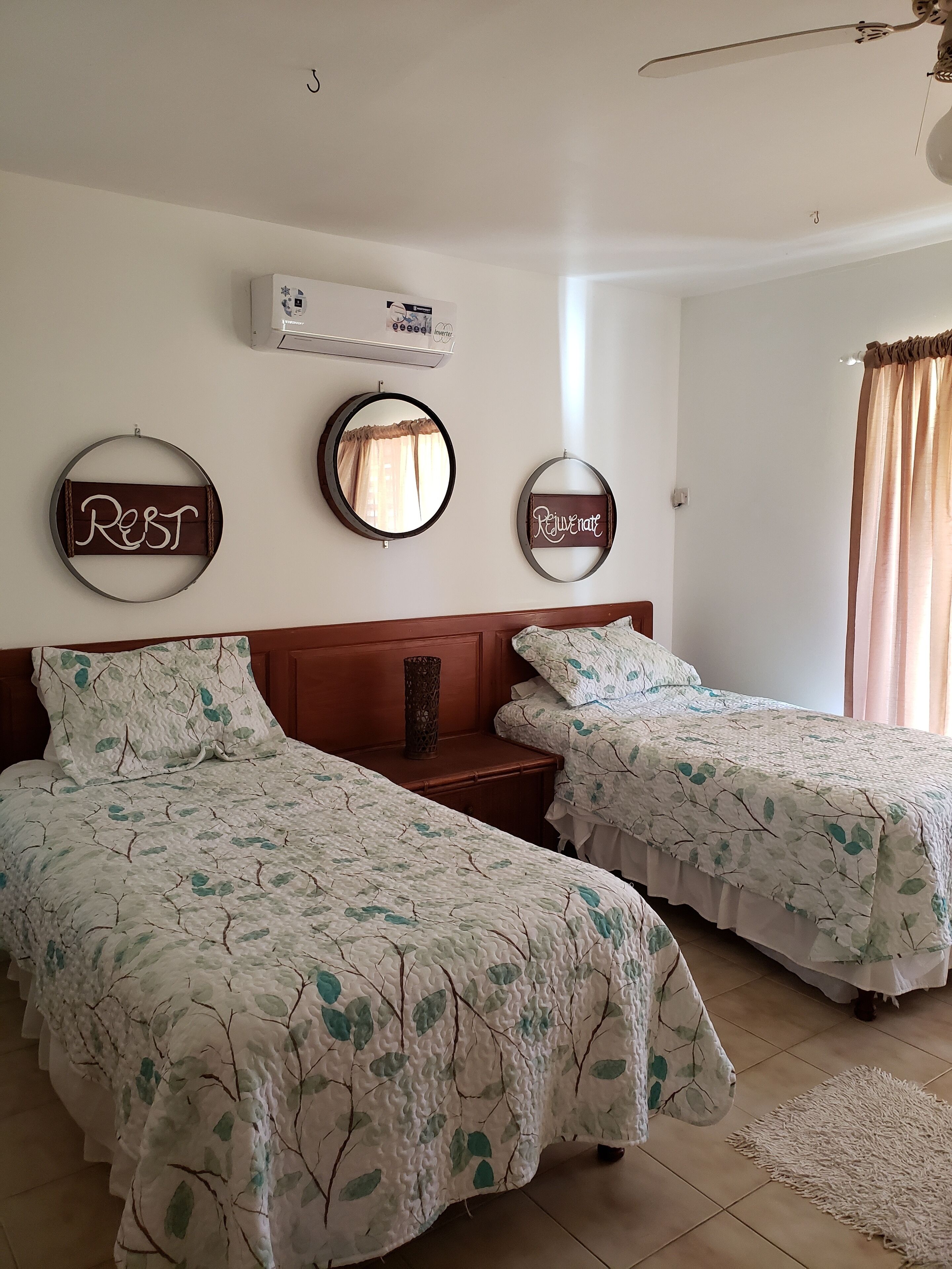 A bedroom with two single beds and an air conditioner.