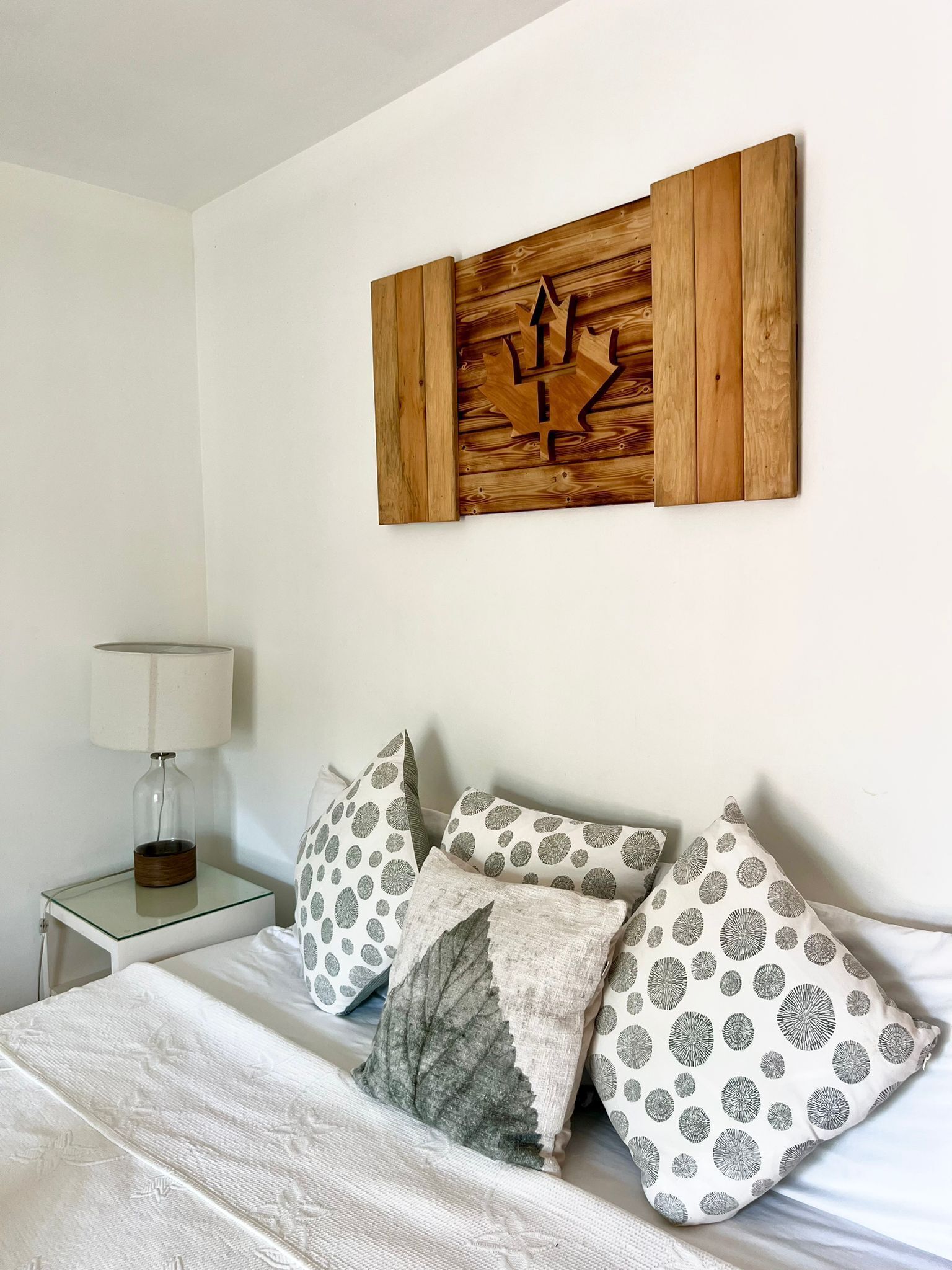A bed with patterned pillows under a wood wall panel.