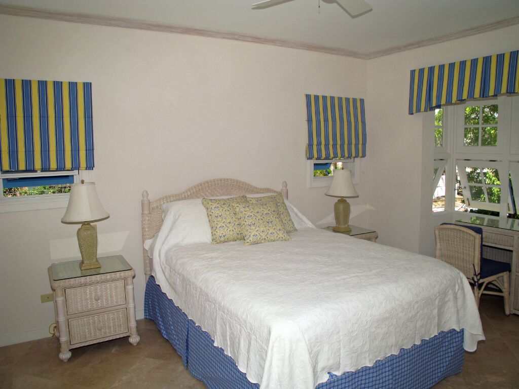 A bedroom with a double bed and striped window blinds.