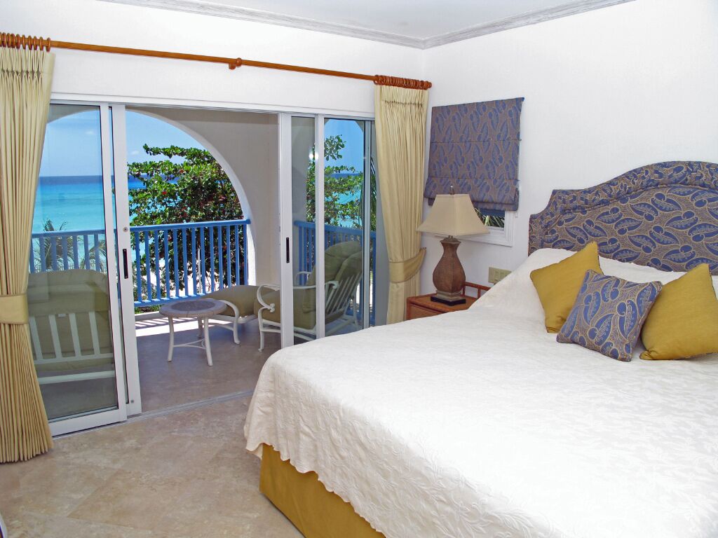 A bedroom with a double bed, with doors open to the balcony.