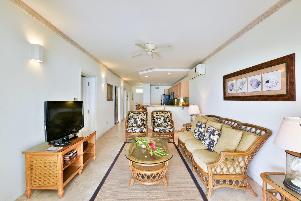 The living room with a television, with the kitchen beyond.