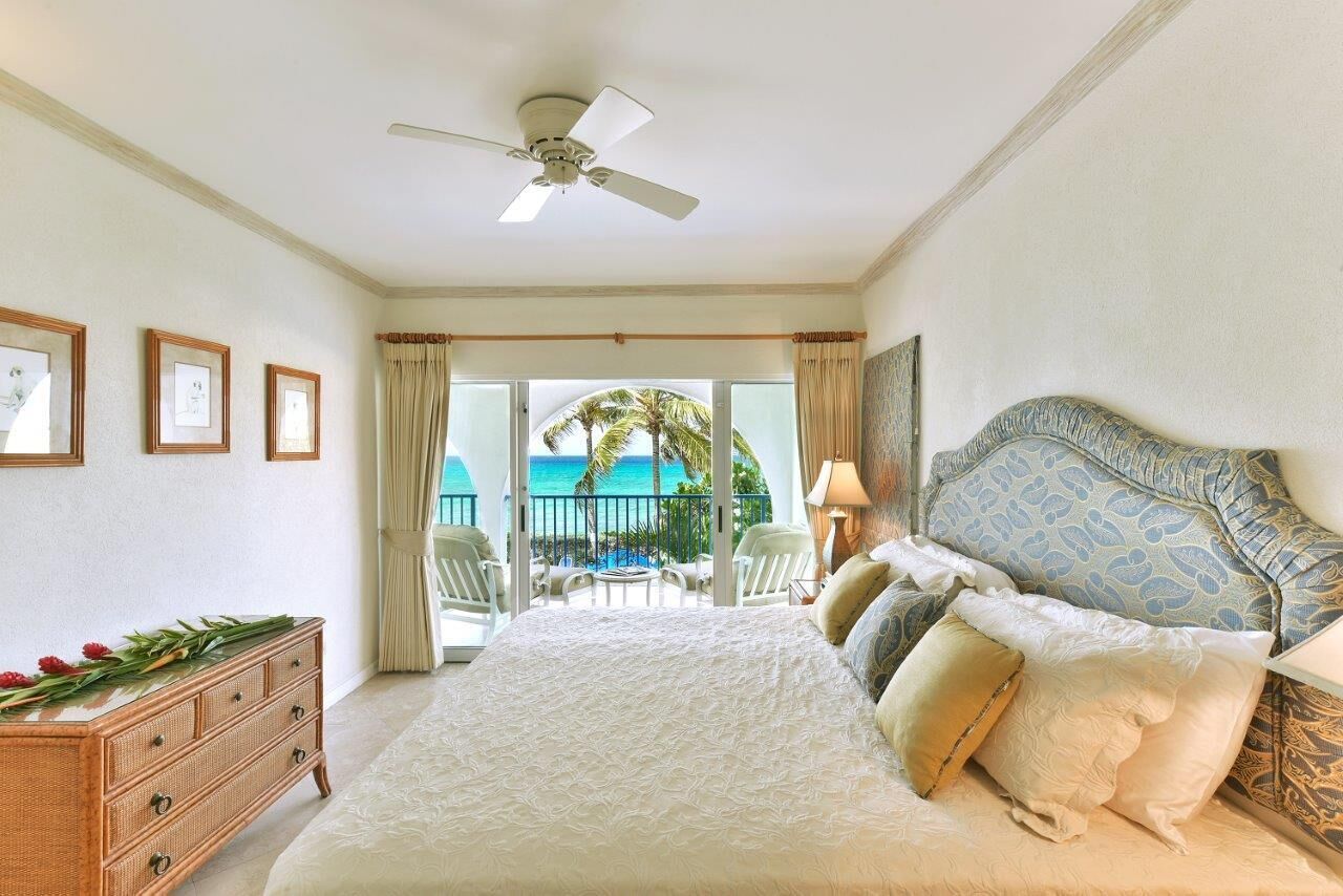 A bedroom with a wide bed and a sea view.