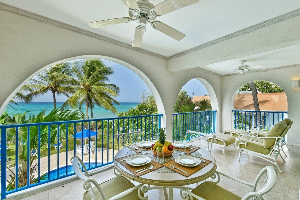 A table set for a meal on the balcony, with a sea view.