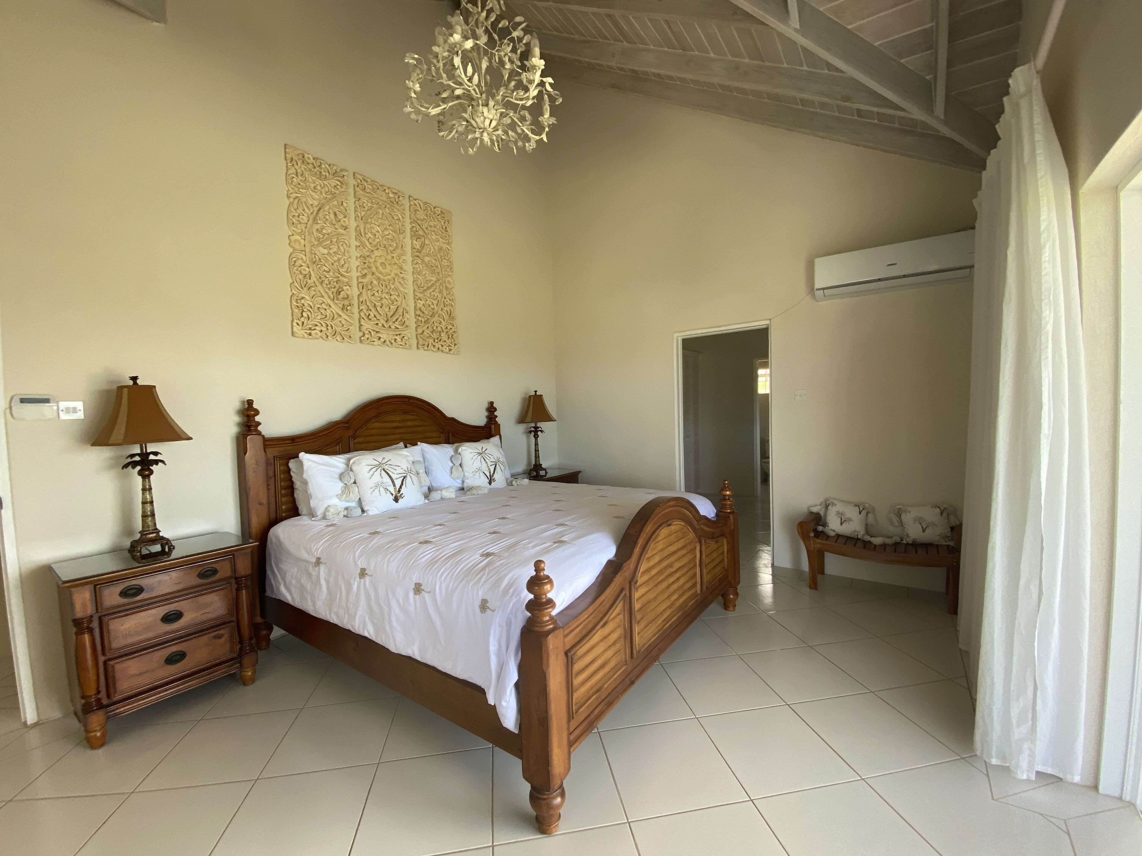 A bedroom with a wooden bed, white bed linen, two lamps, and carved wall panels.