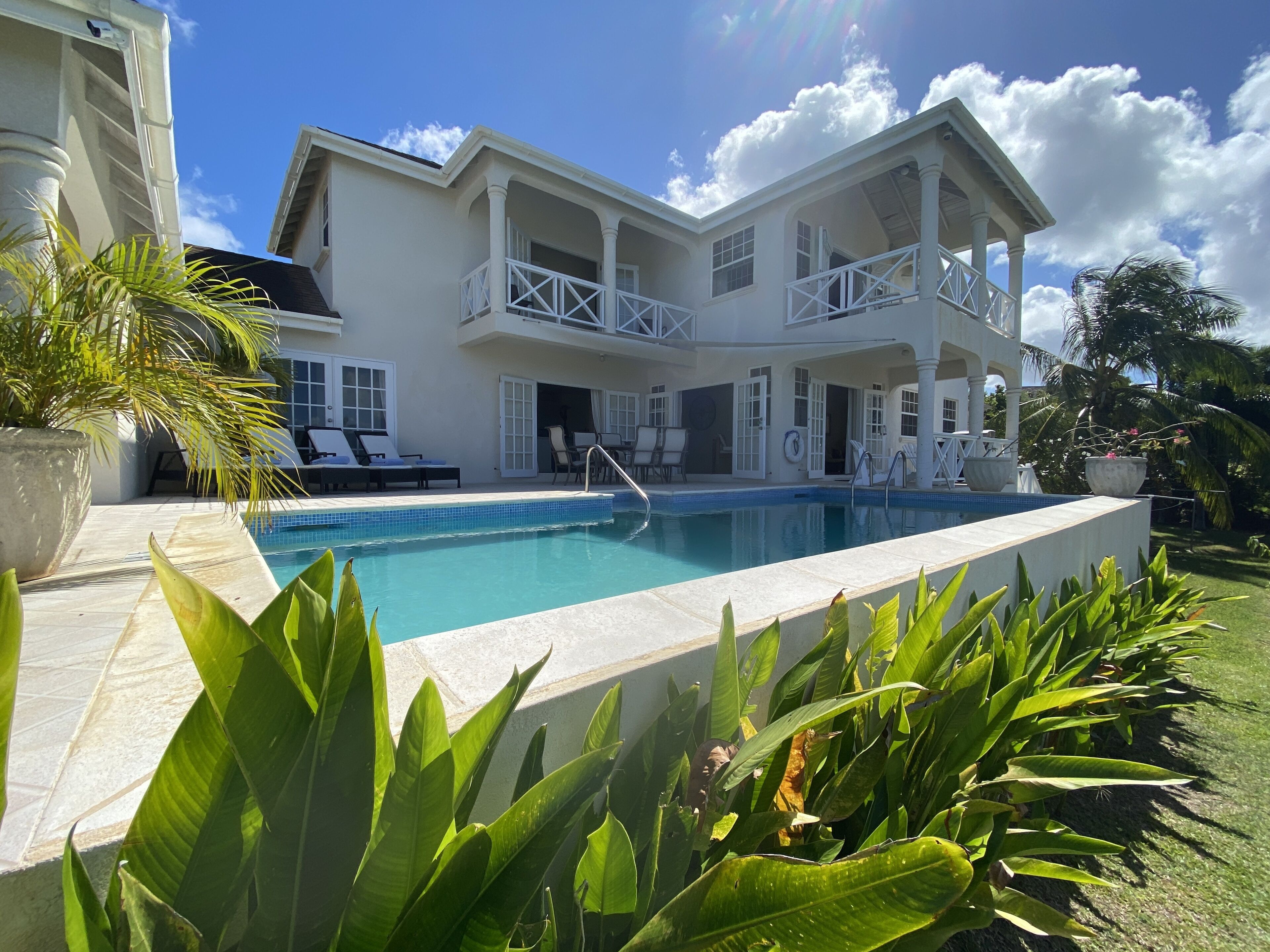 The two-story villa with balconies, the pool, and the terrace in front.