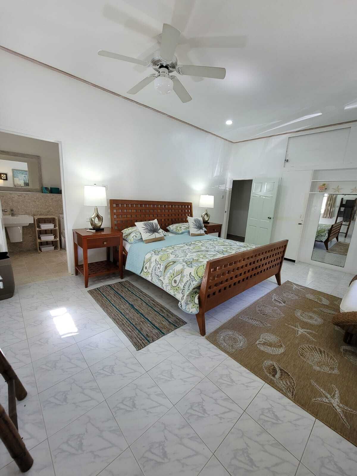 A bedroom with a wood king bed and an open door to a bathroom.