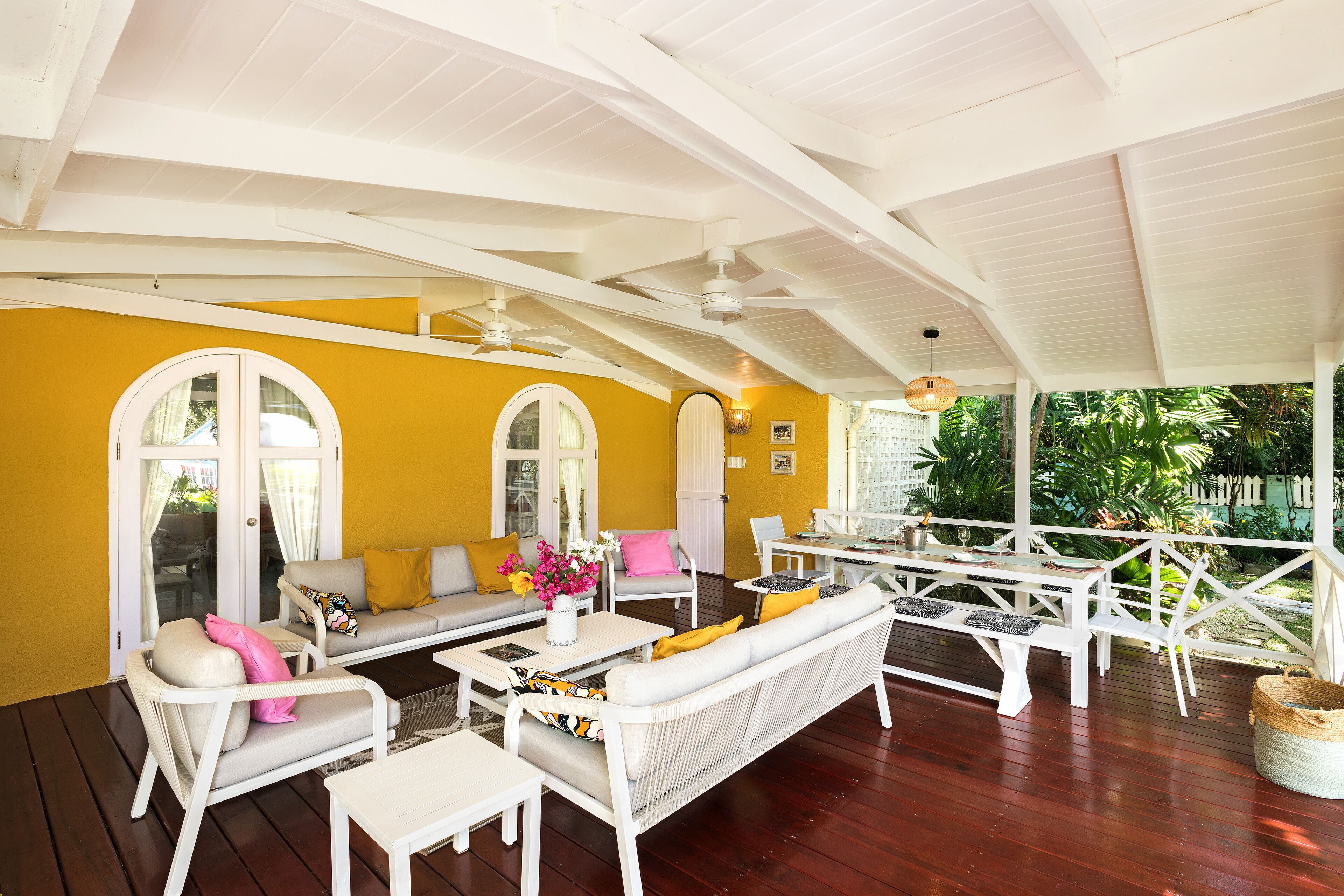 The covered veranda with white sofas, a coffee table, and a dining table.