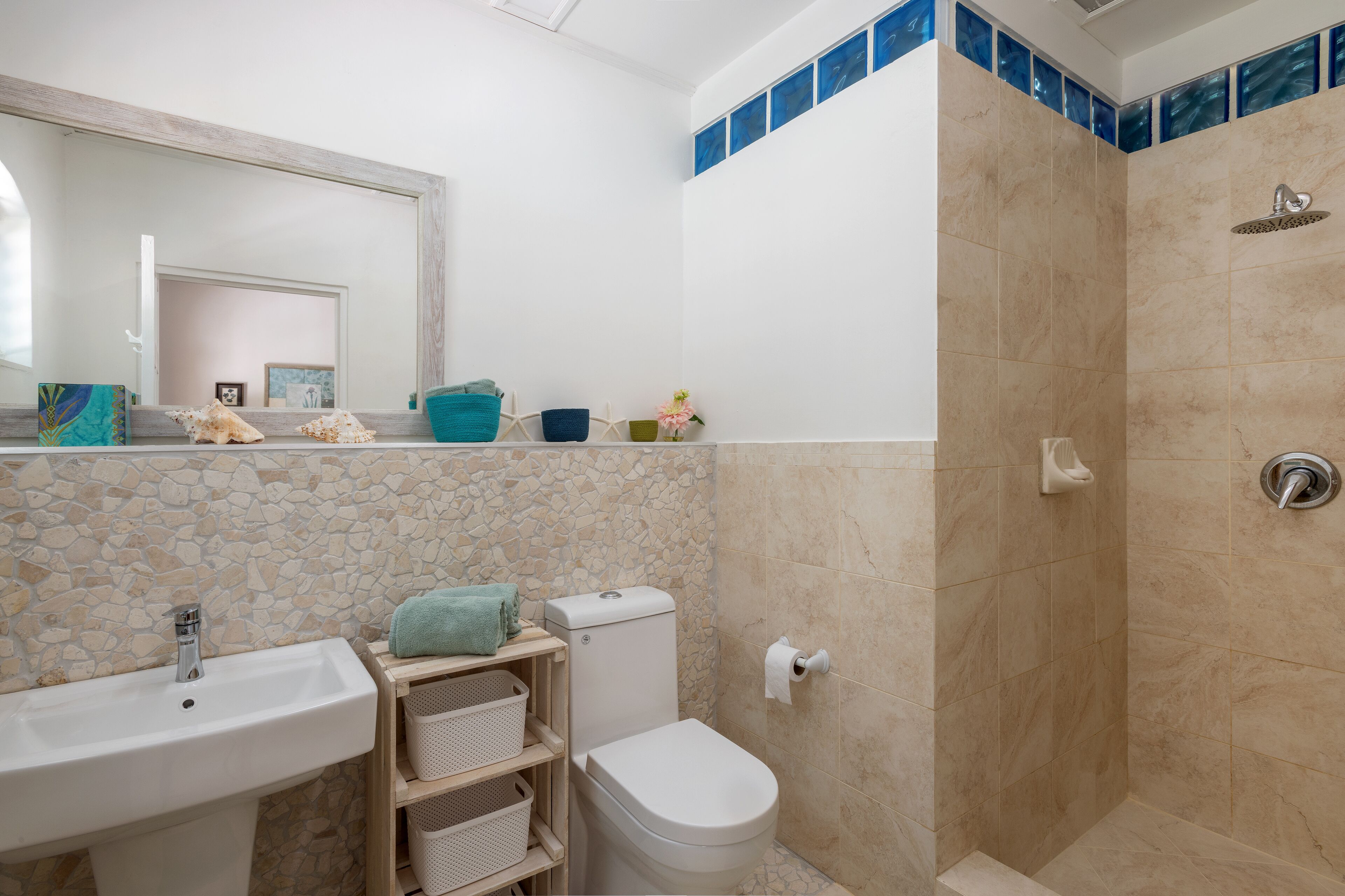 A bathroom with a sink, a toilet, and a stone tile shower.