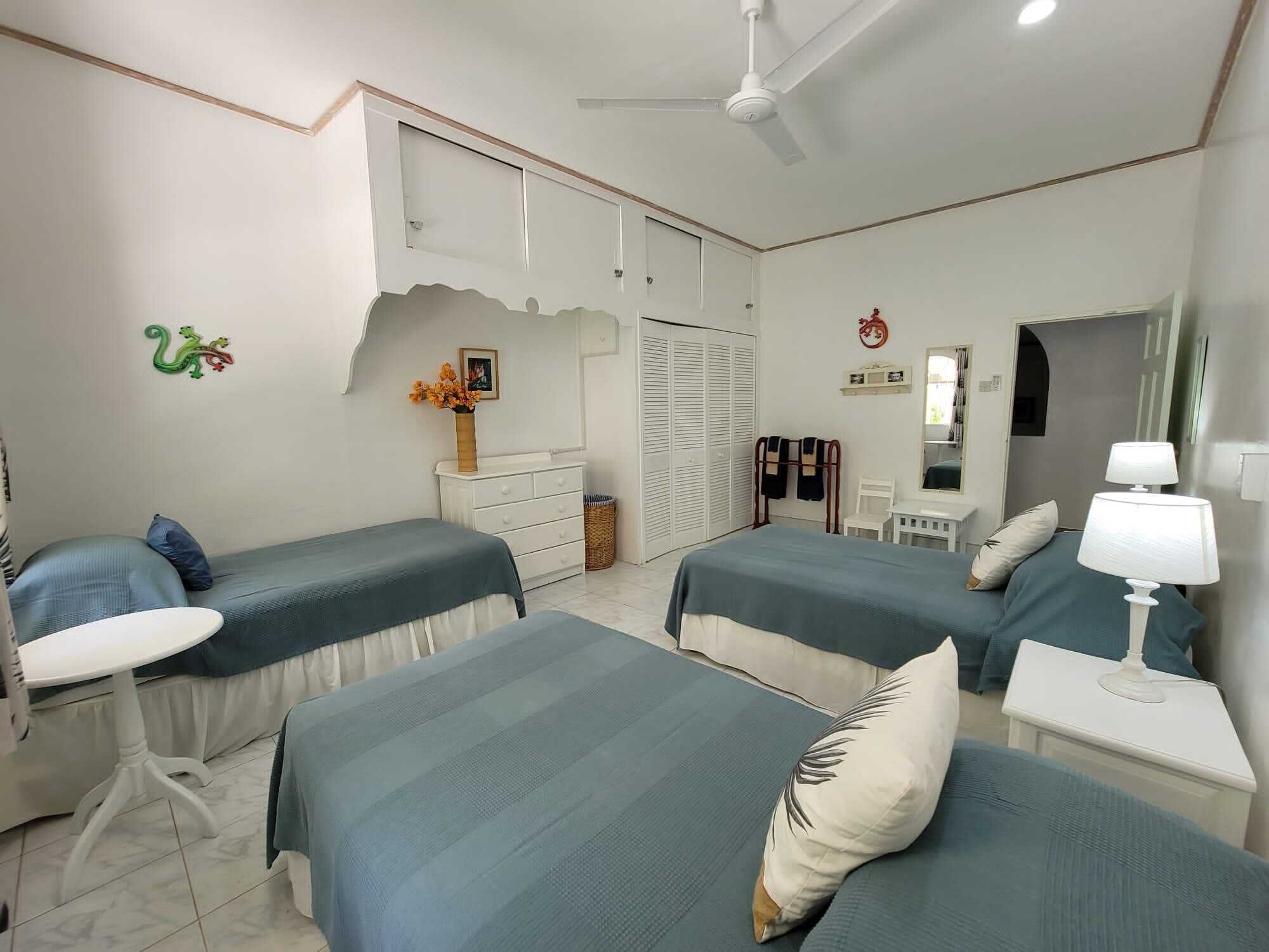 A bedroom with three single beds and a ceiling fan.