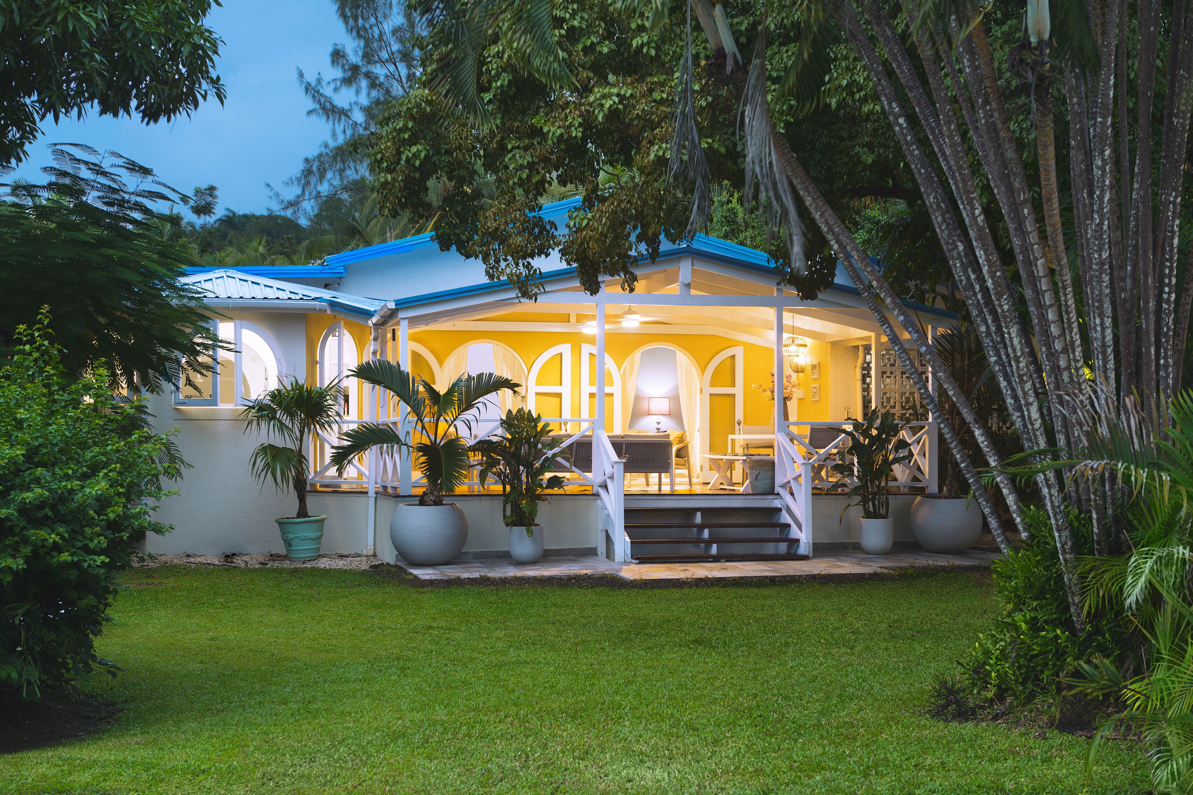The villa at dusk with lights on inside the veranda.
