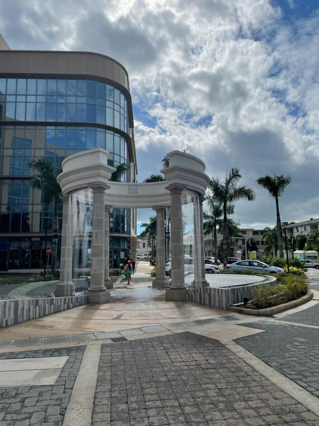 A fountain with stone columns in front of a glass building in Nassau.