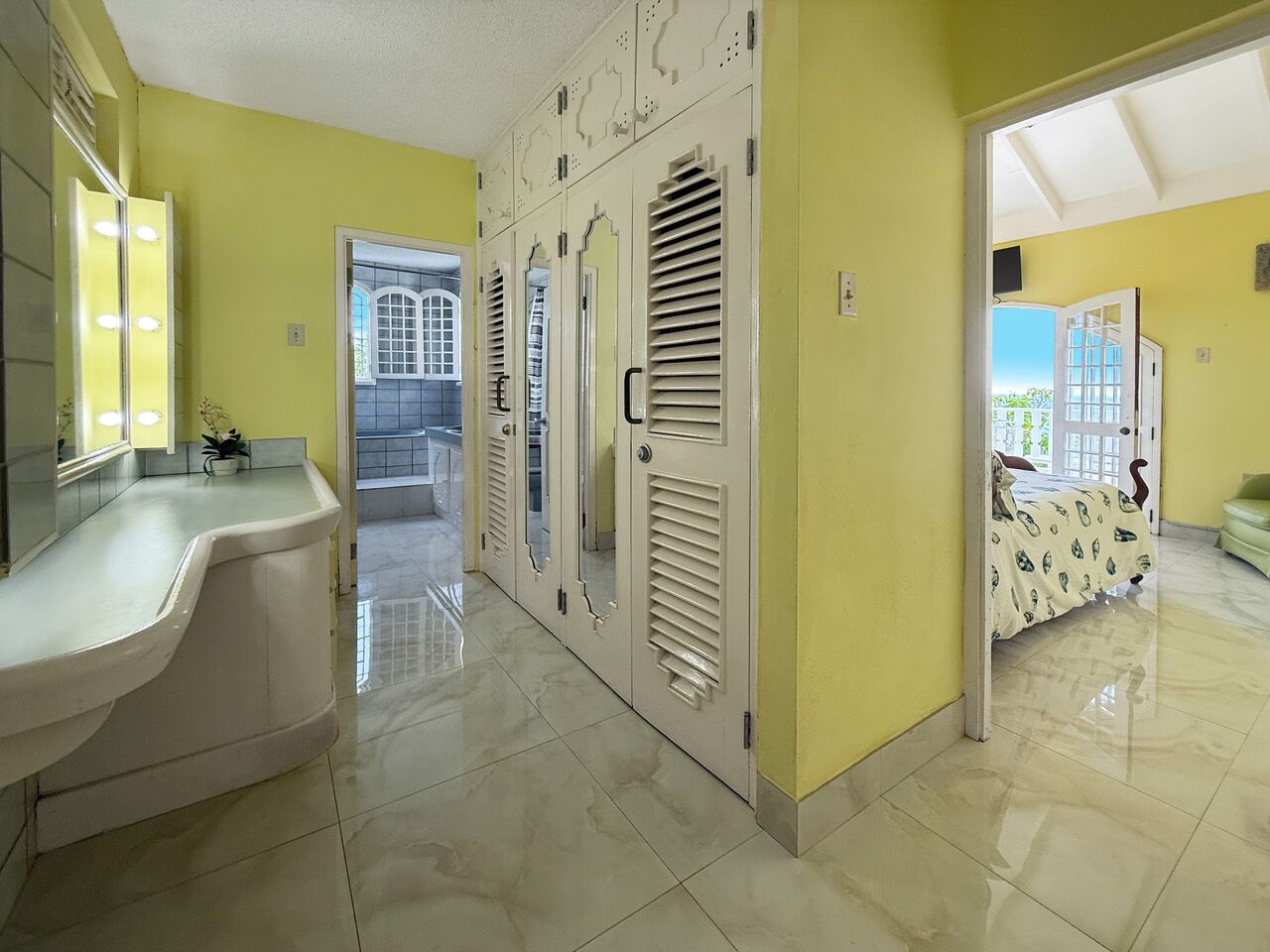 A dressing area with a vanity, closets, and doors to the bathroom and a bedroom.