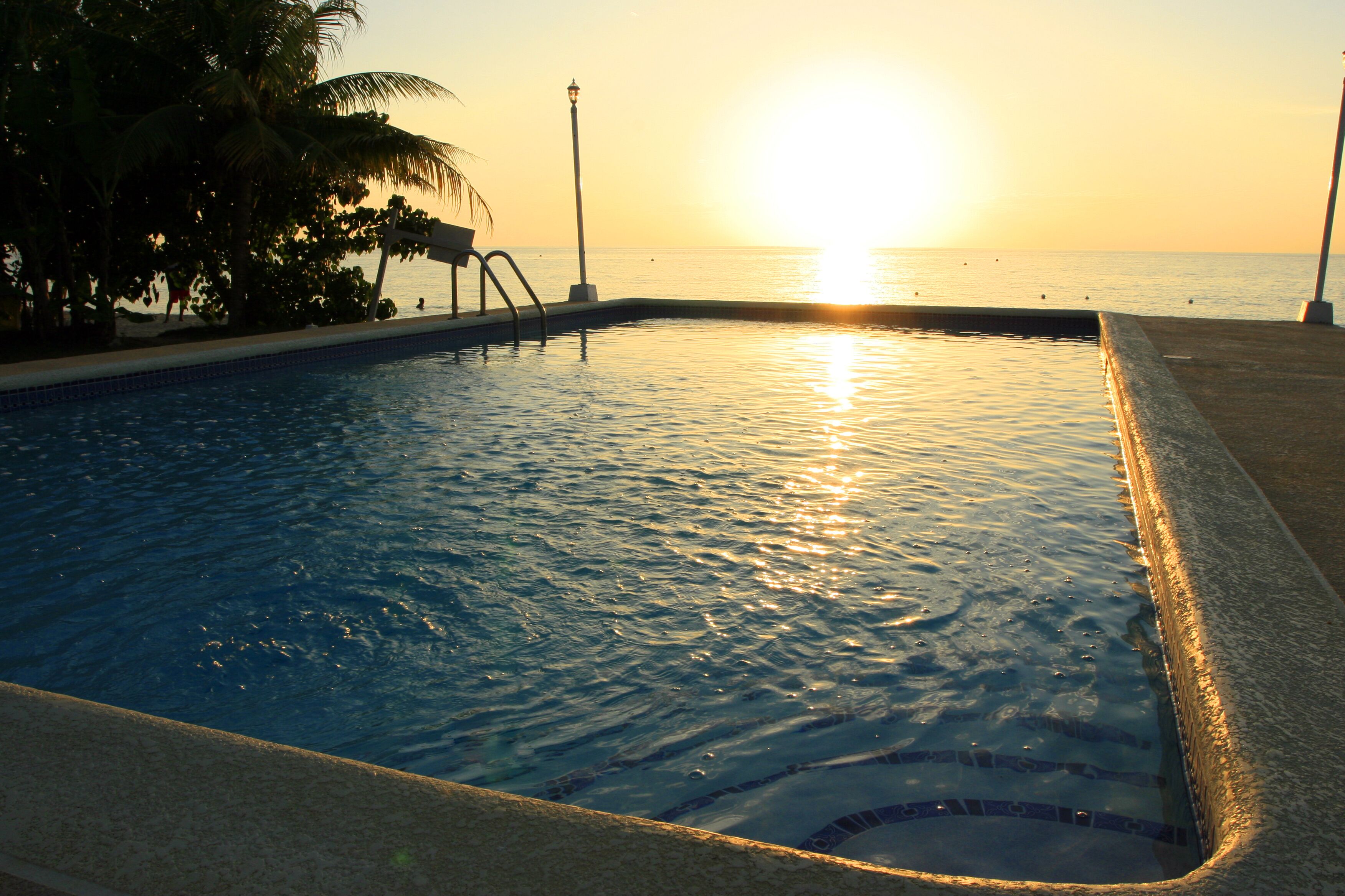 The pool at sunset with the sun low over the sea.
