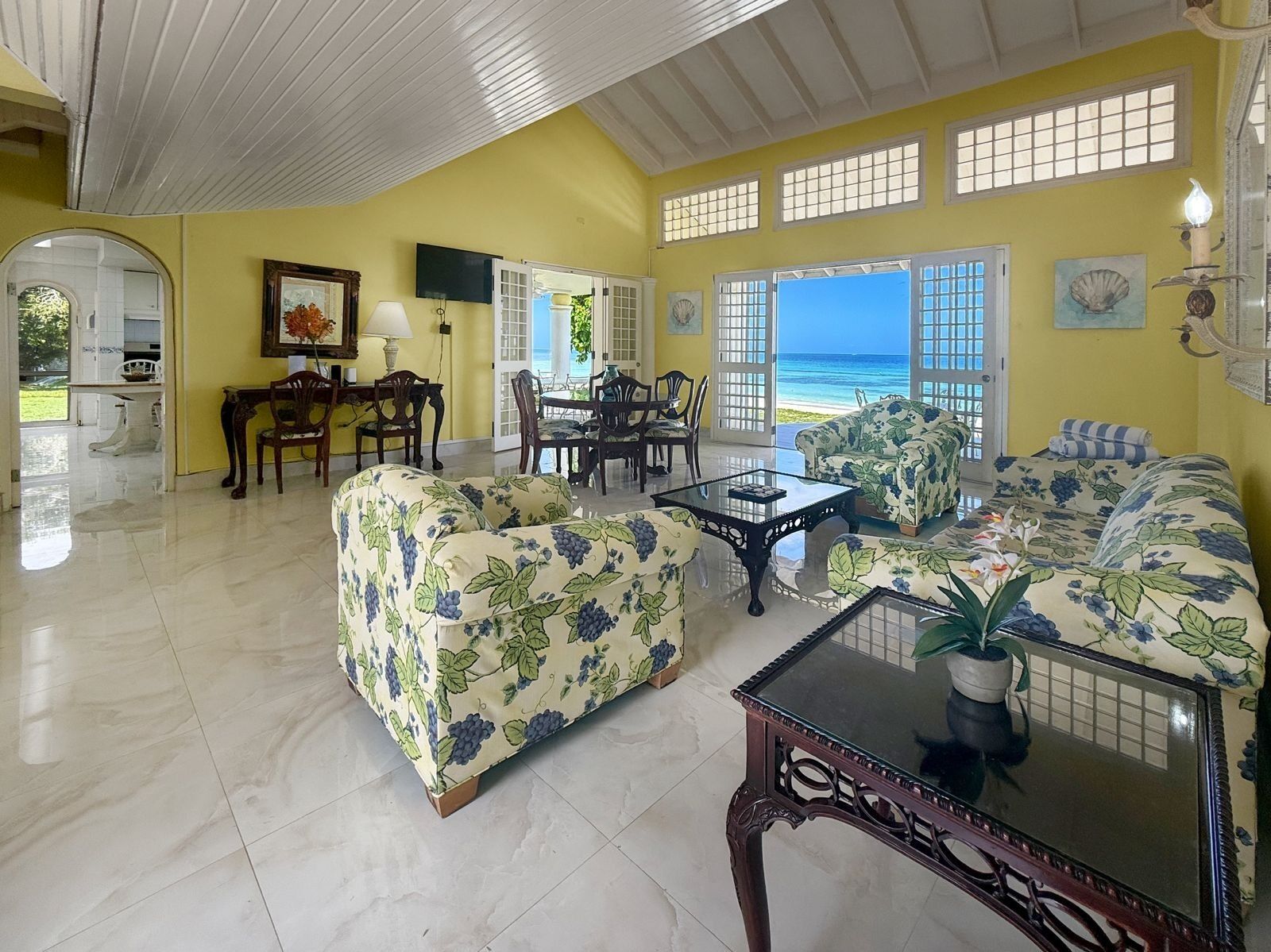 The living room with floral sofas and open doors to the sea.