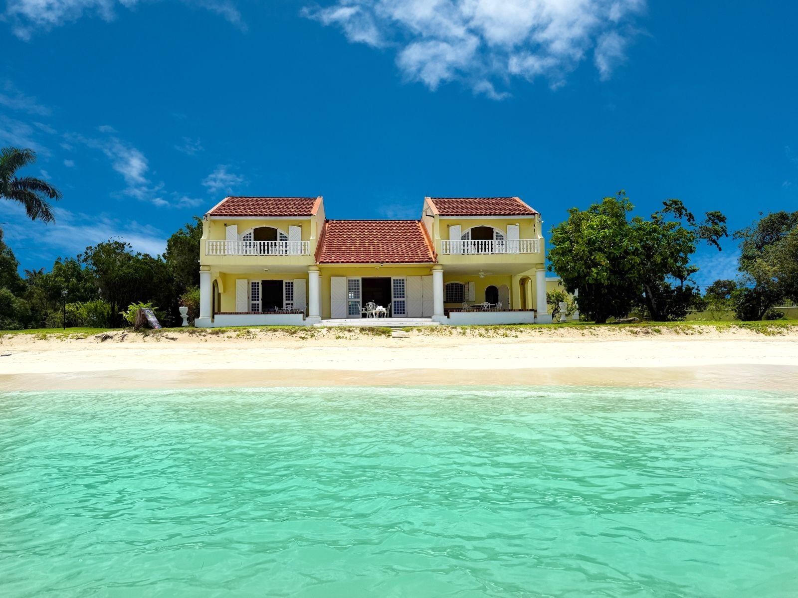 The villa seen from the water with the beach in front.