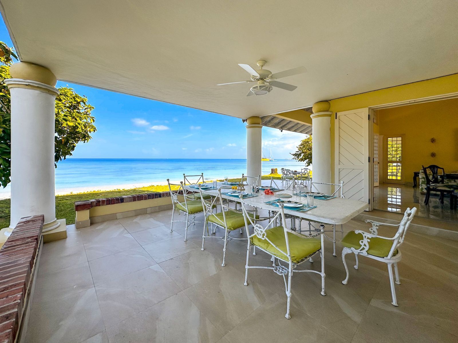 The covered veranda with a dining table, a ceiling fan, and a sea view.