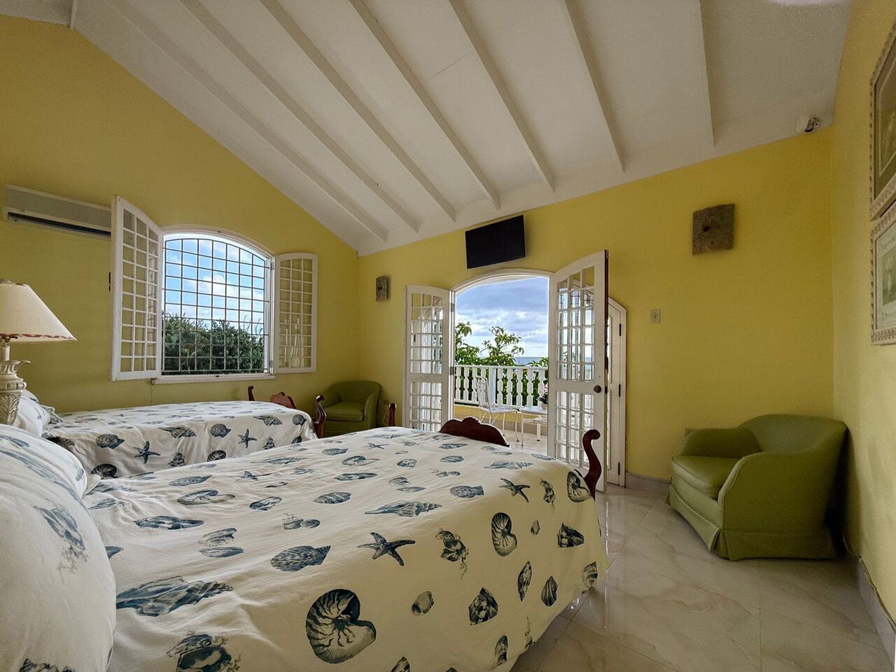 A bedroom with two beds and open doors to a balcony.