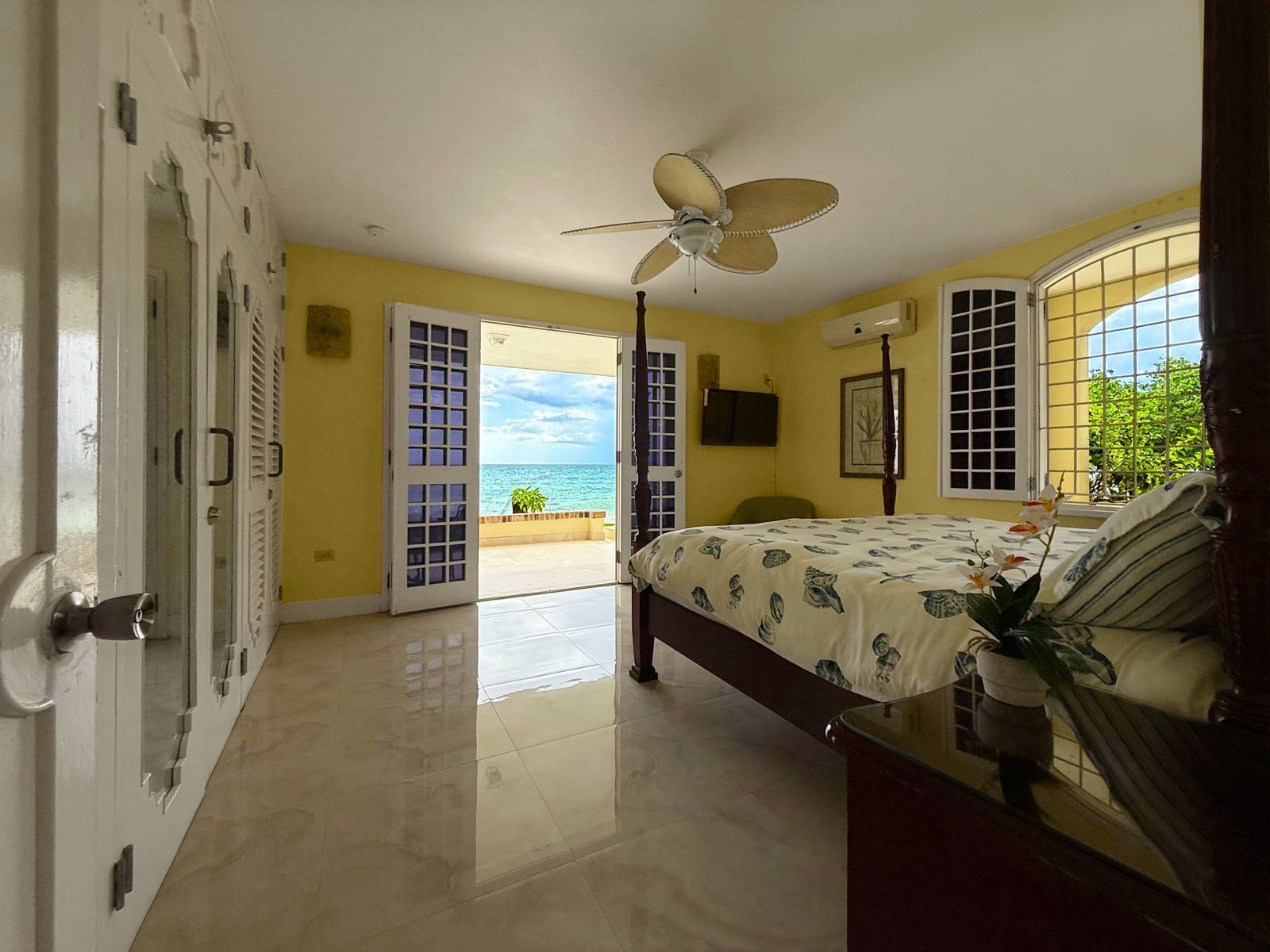 A bedroom with closets and open doors to a terrace with a sea view.