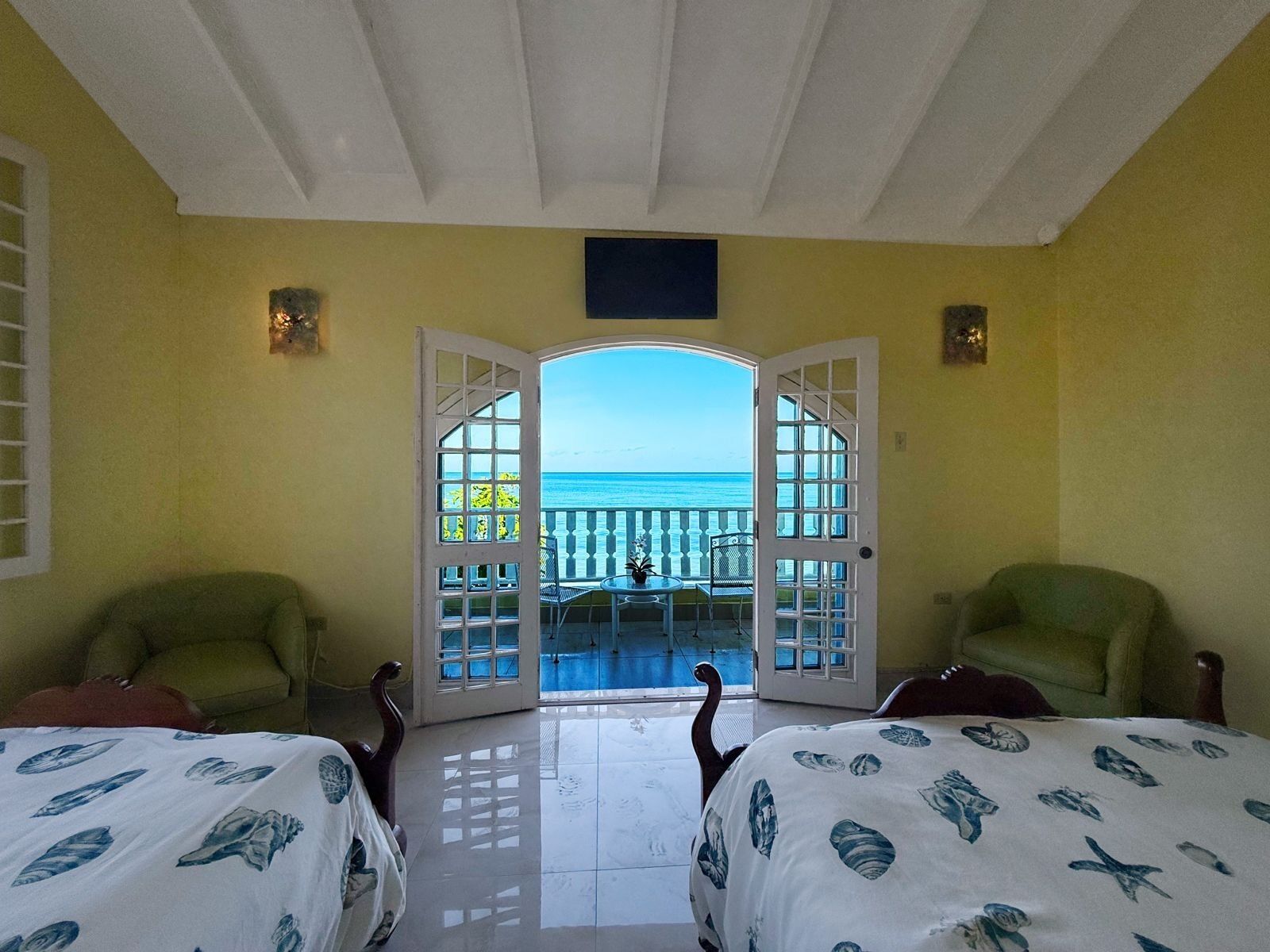 The villa seen from the beach with balconies and a red tile roof.