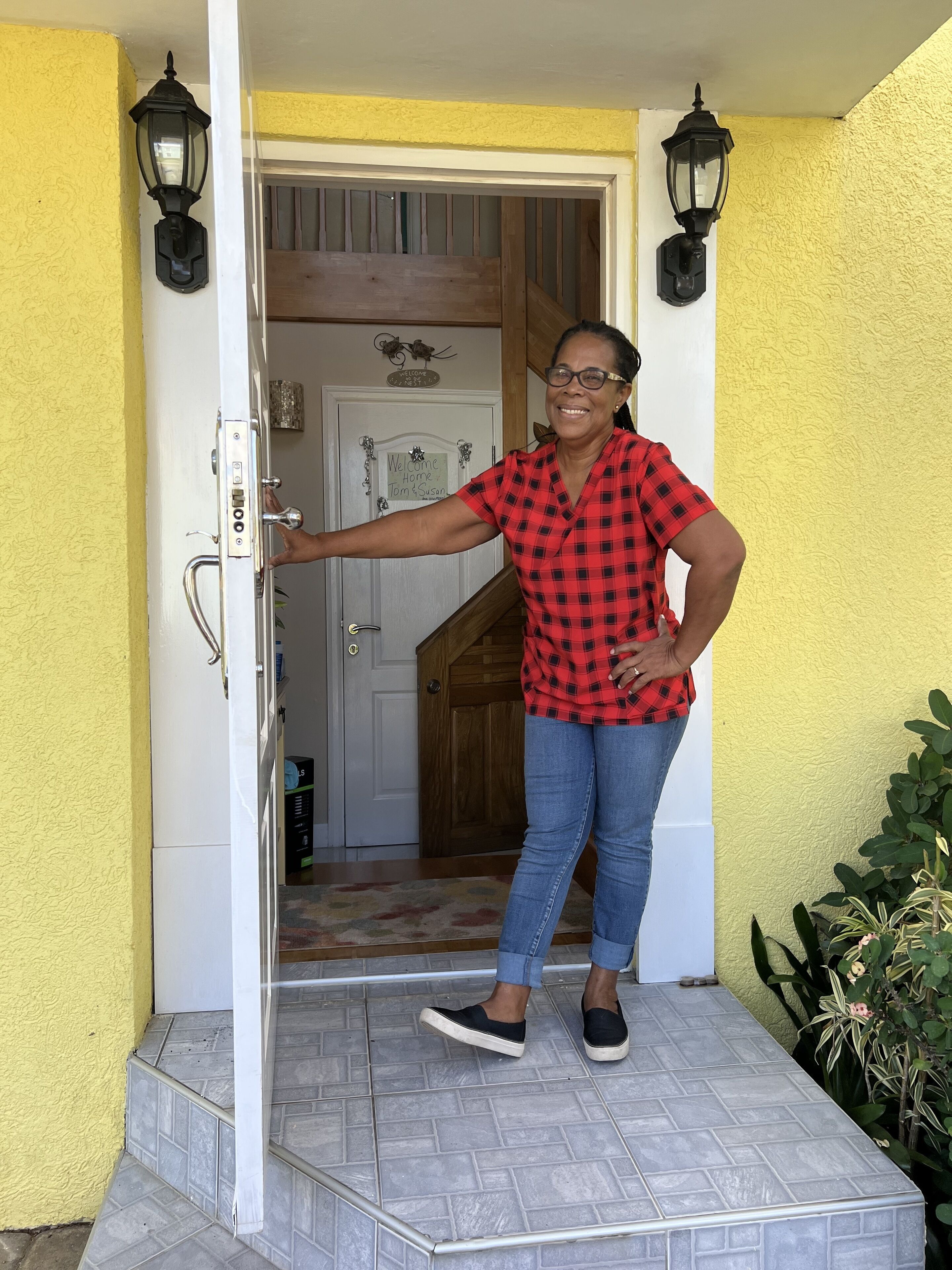 A woman opens the white front door of the townhome.