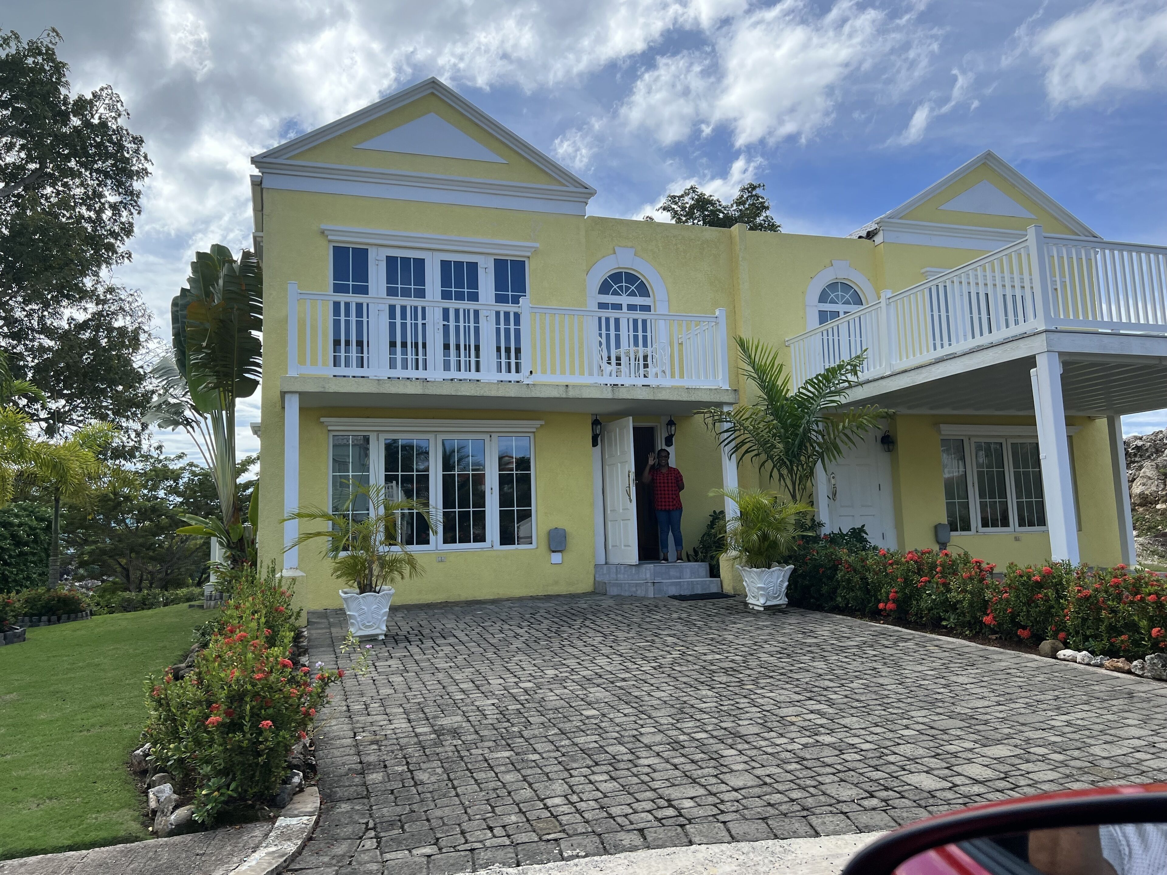 The yellow townhome has white balconies and a paved driveway.