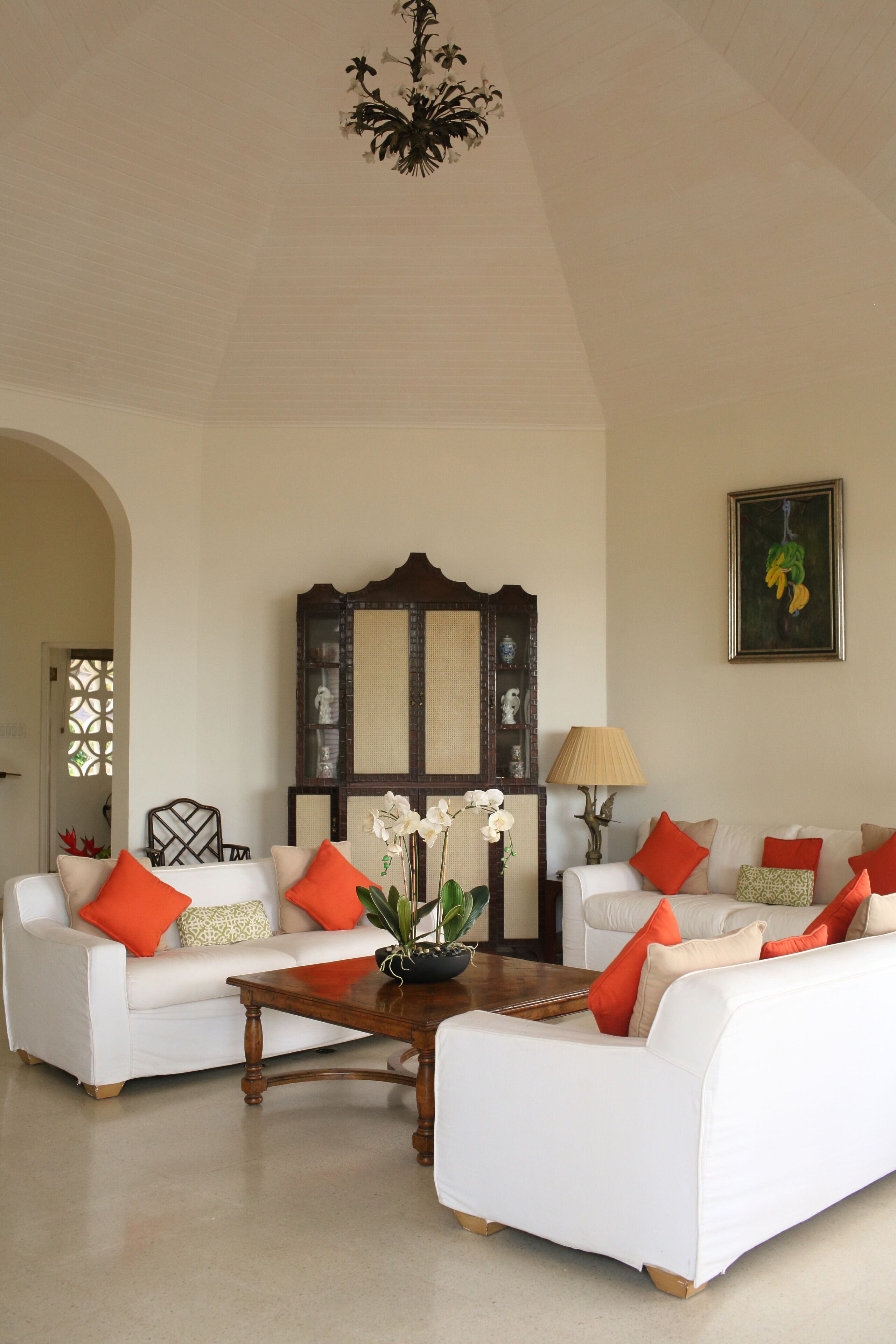 The living room with white sofas, orange pillows, and a wood coffee table.