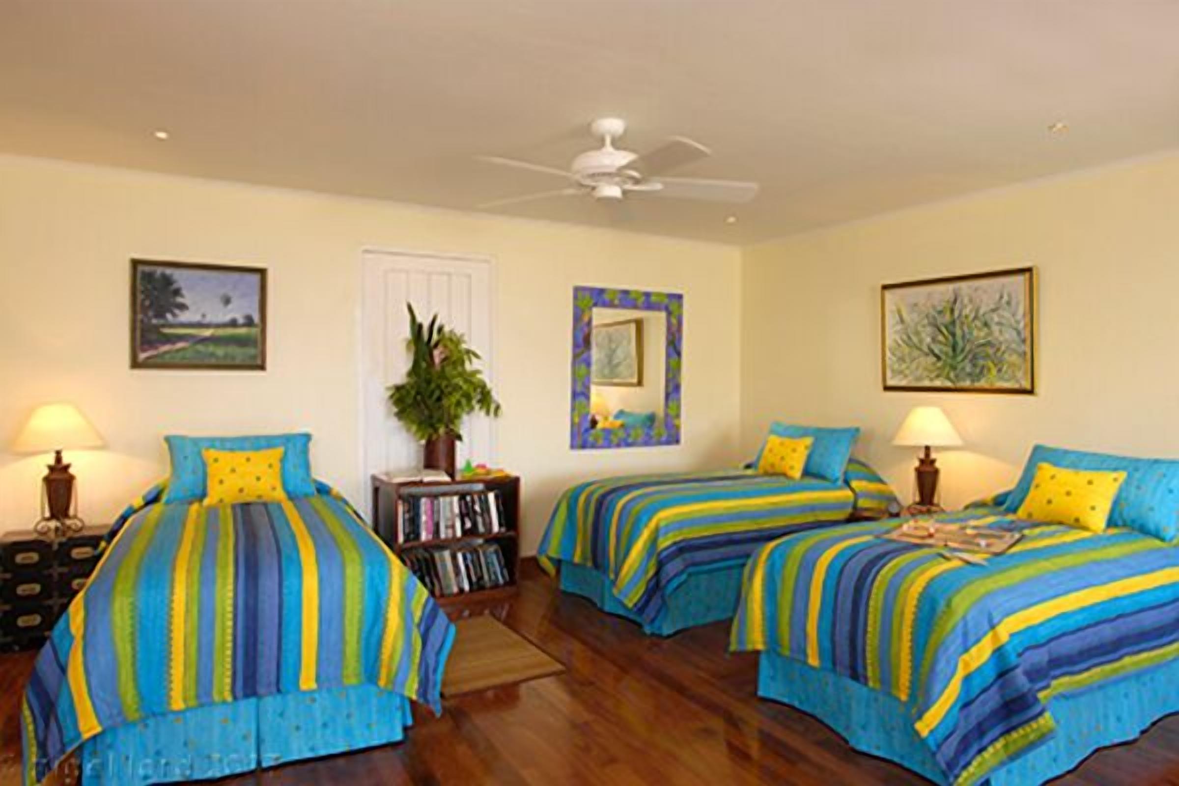 A bedroom with three single beds with striped covers.