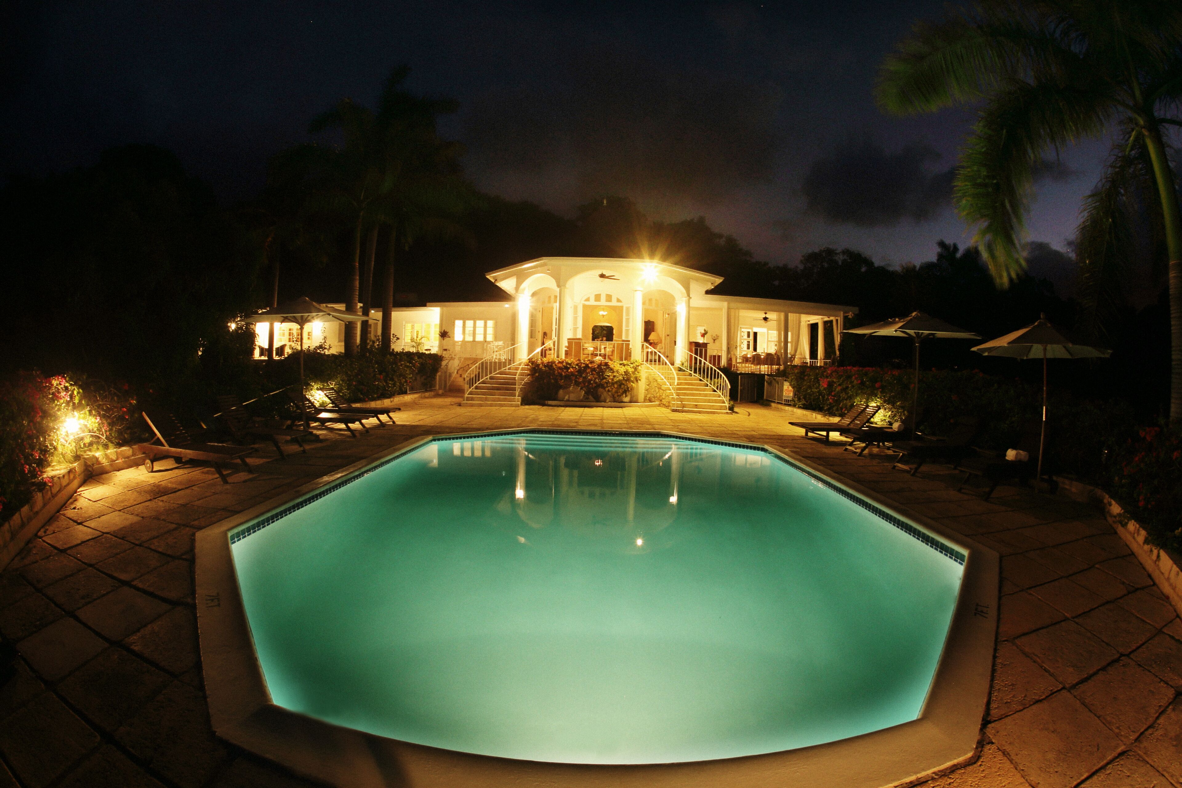 The pool and the lit villa at night.