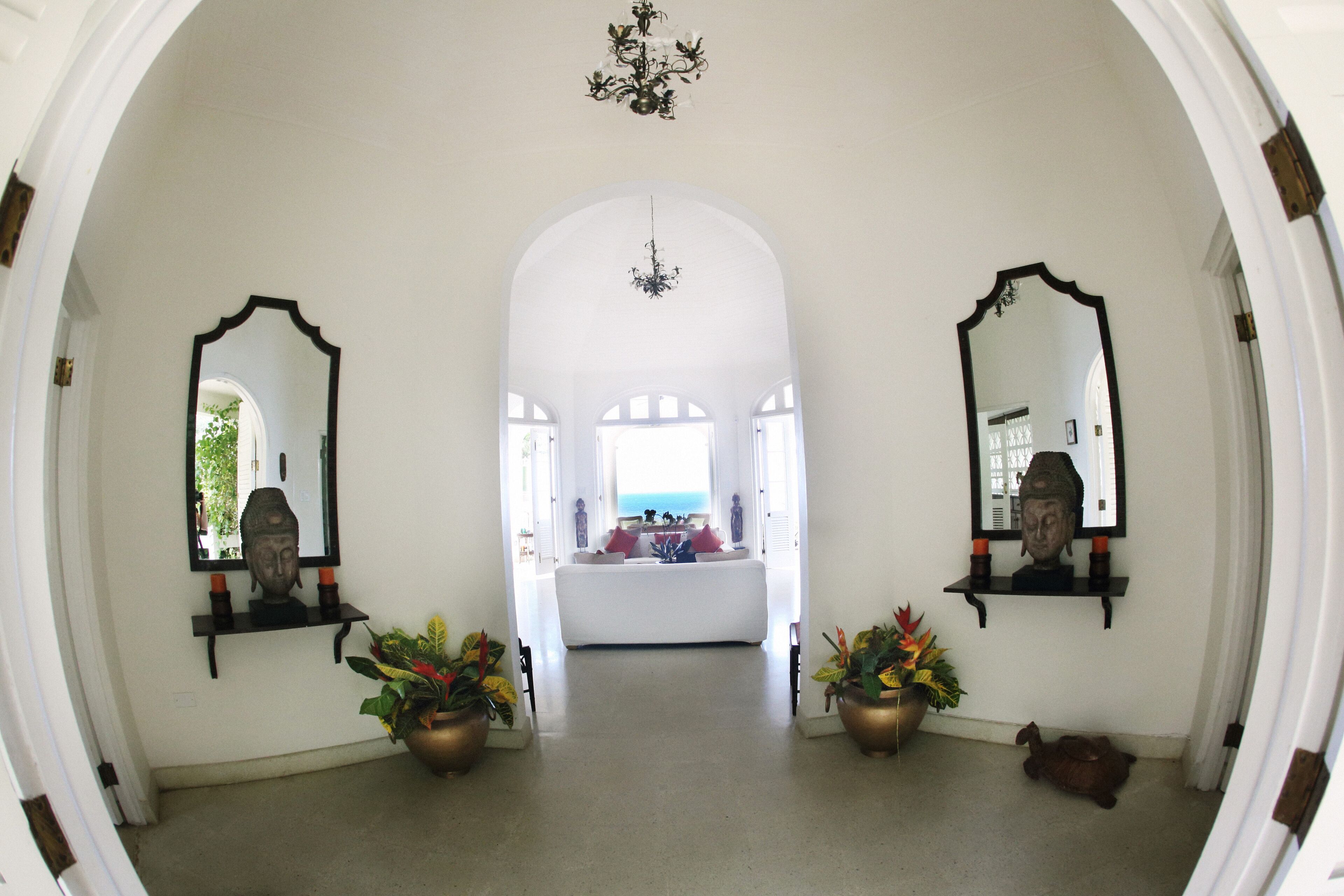 The entry hall with two mirrors, potted plants, and a view to the sea.