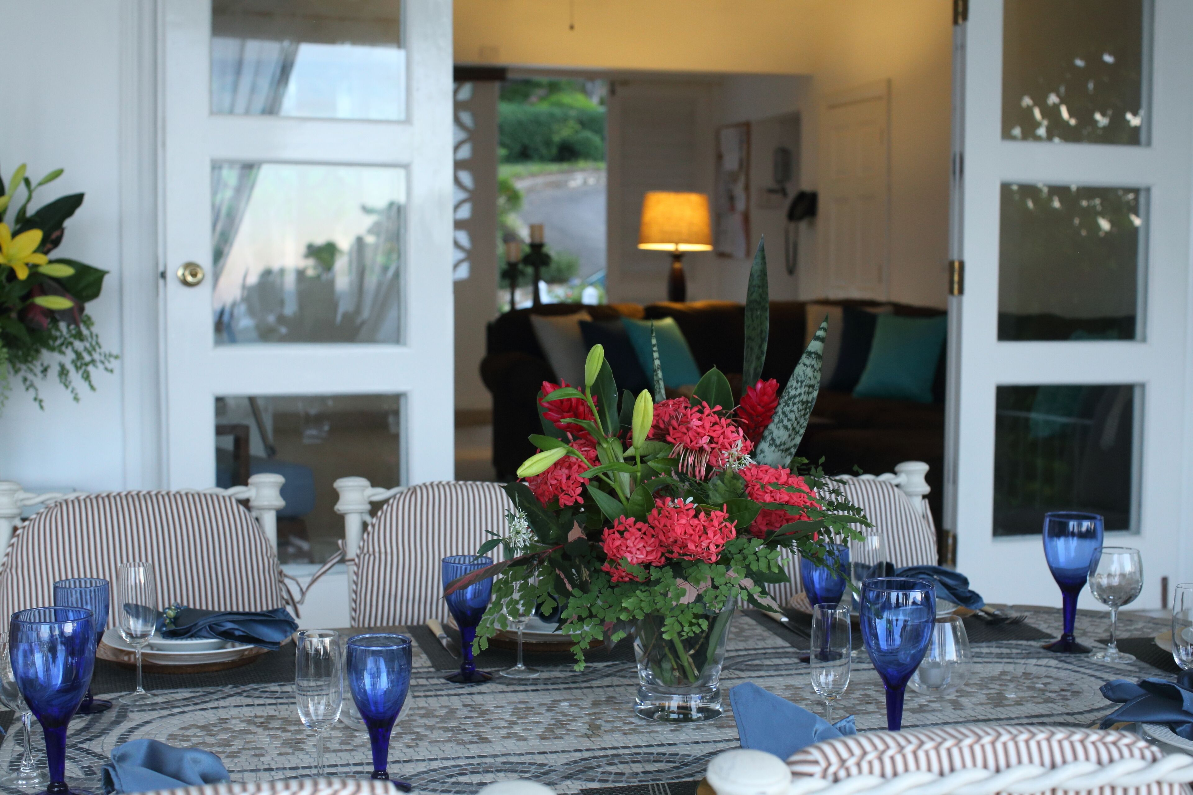 A table on the veranda set with blue glasses and a flower centerpiece.