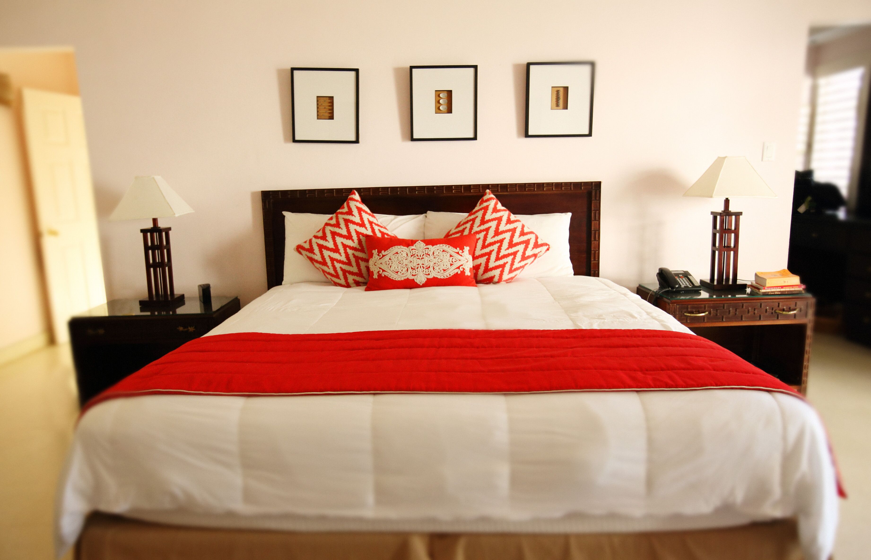 A bedroom with a large bed with red and white covers and pillows.
