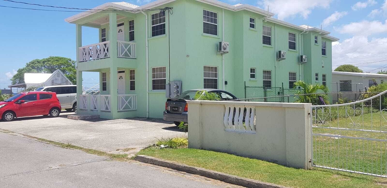 The green apartment building, with balconies and a driveway.