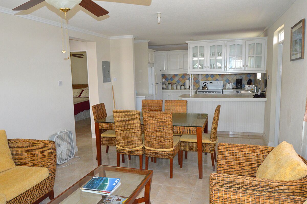 The dining table with wicker chairs, next to the kitchen counter.