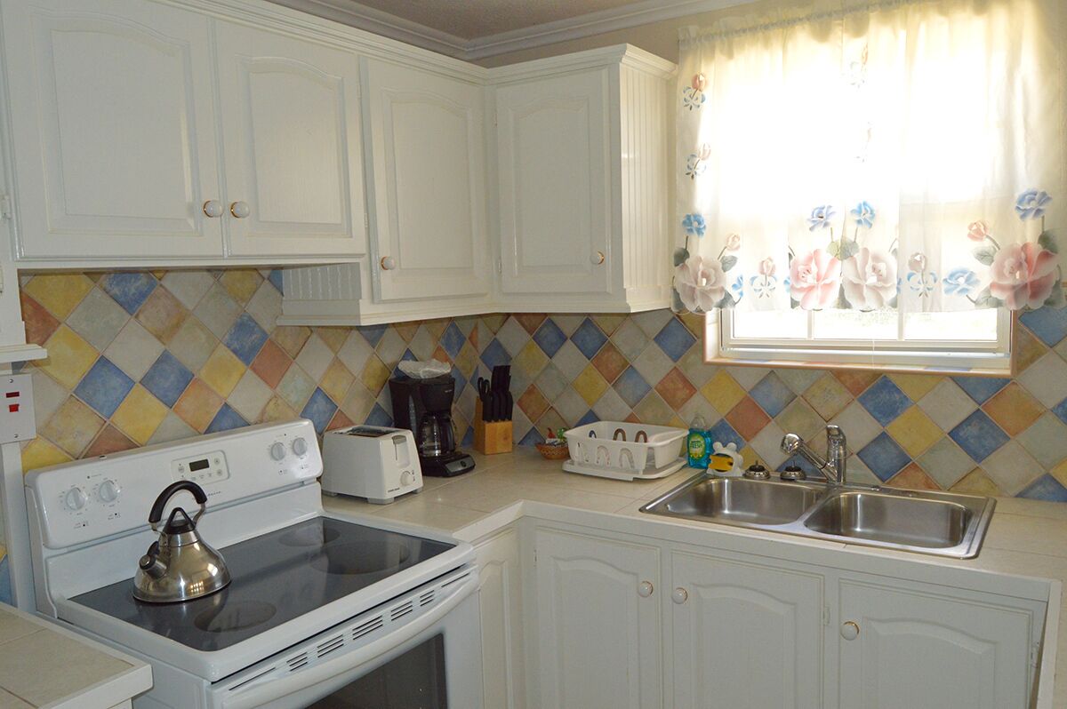 The kitchen with a stove, a toaster, and a double sink.