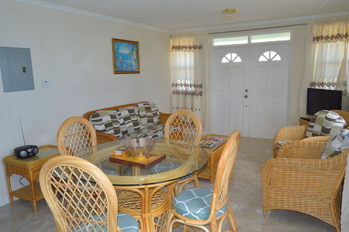 The living room with a wicker sofa and a round glass table.