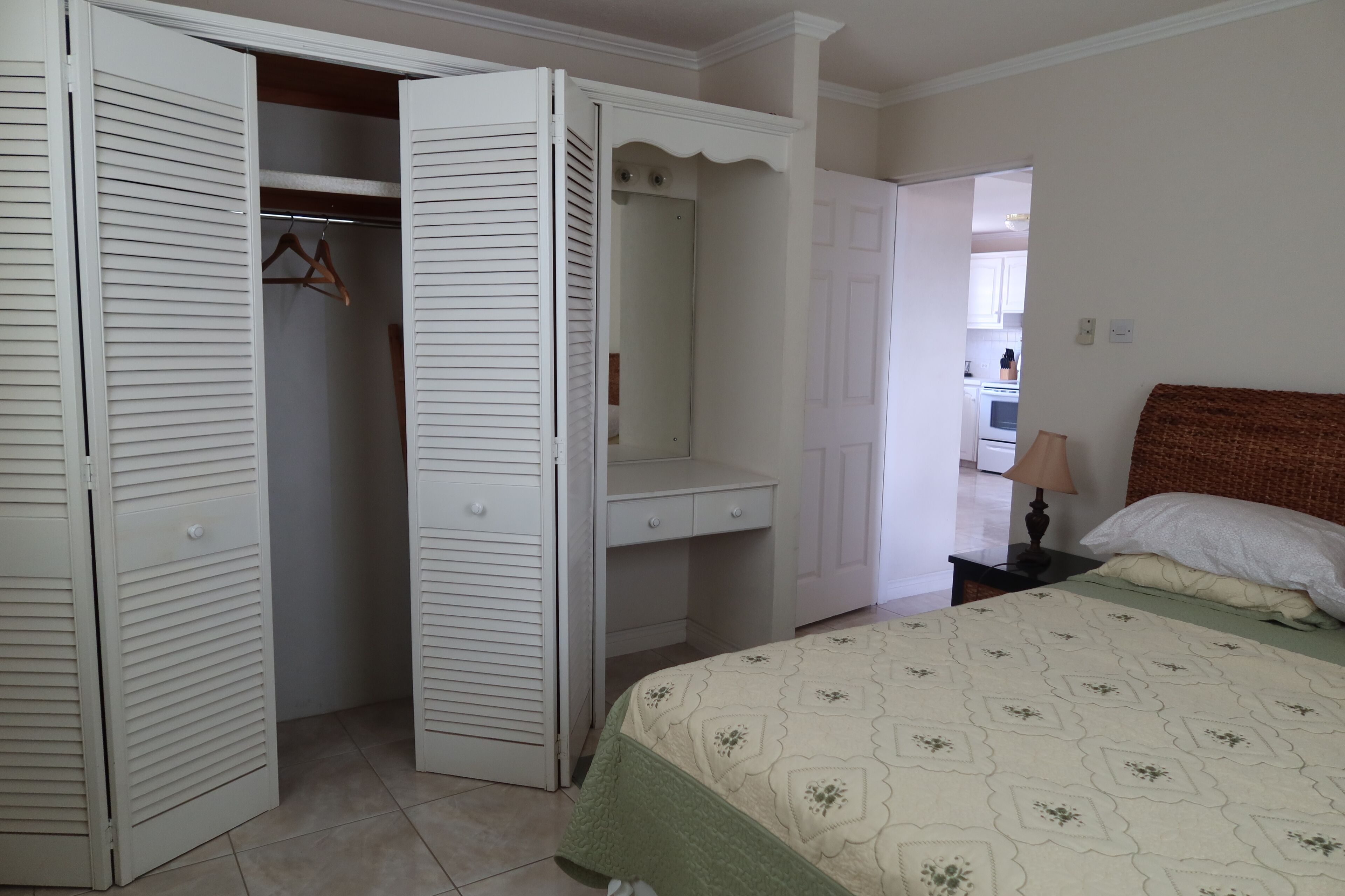 A bedroom with a closet, a vanity table, and a double bed.