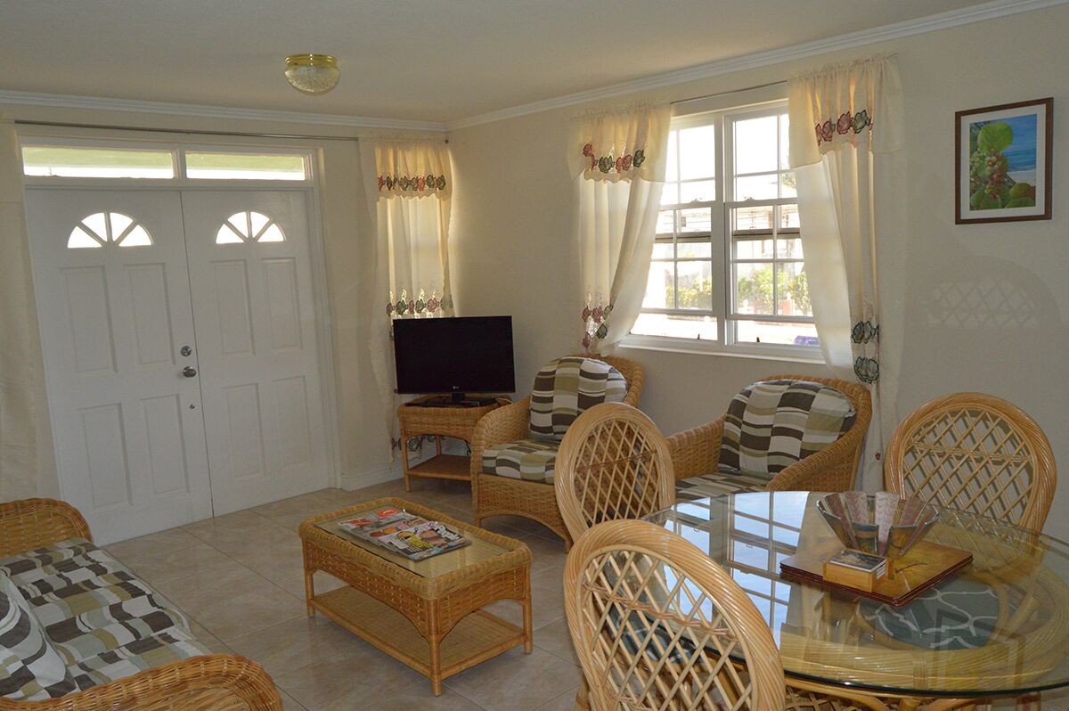 The living room with wicker seats, a television, and double doors.