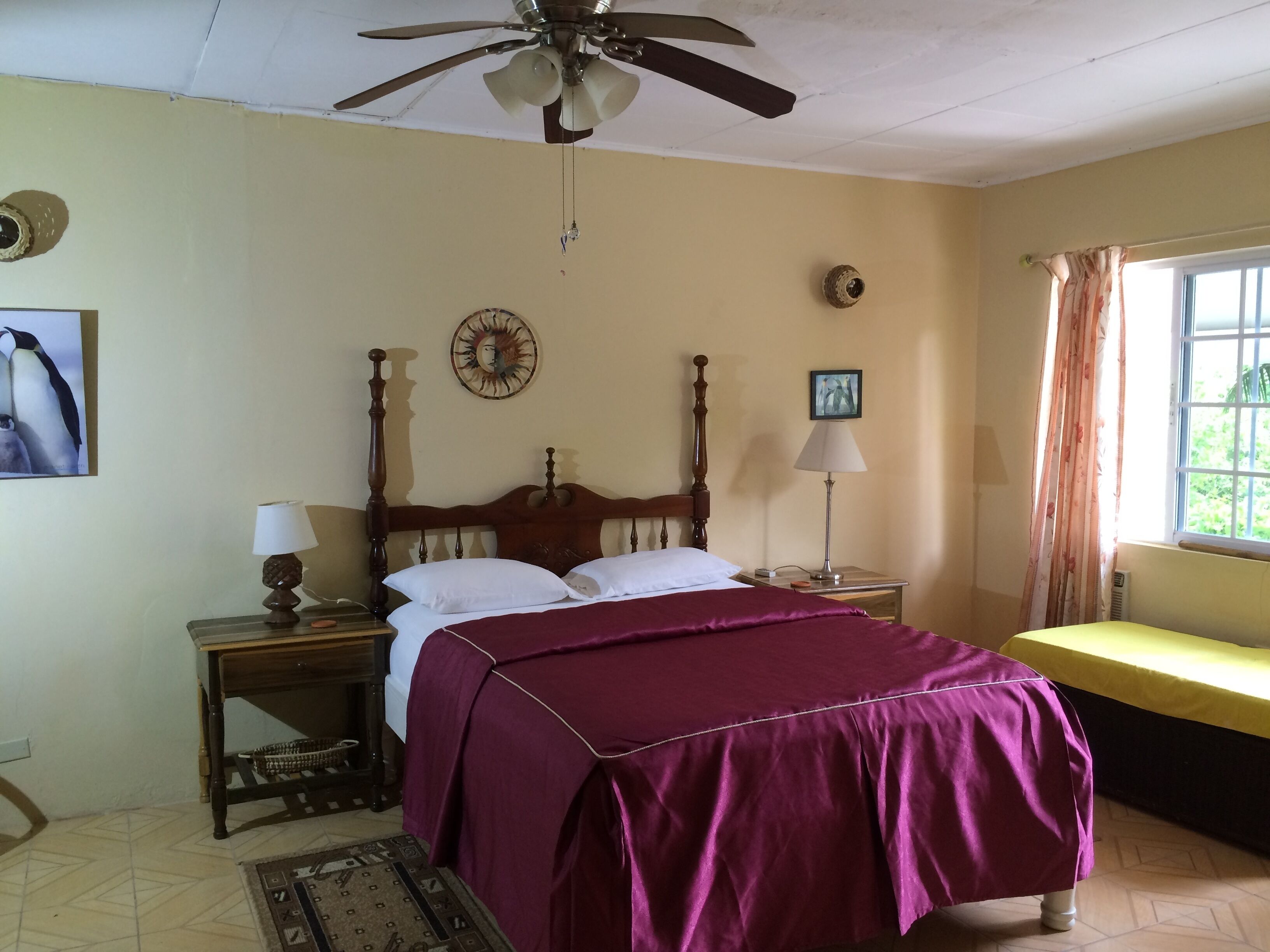 A bedroom with a four-poster double bed and a ceiling fan.