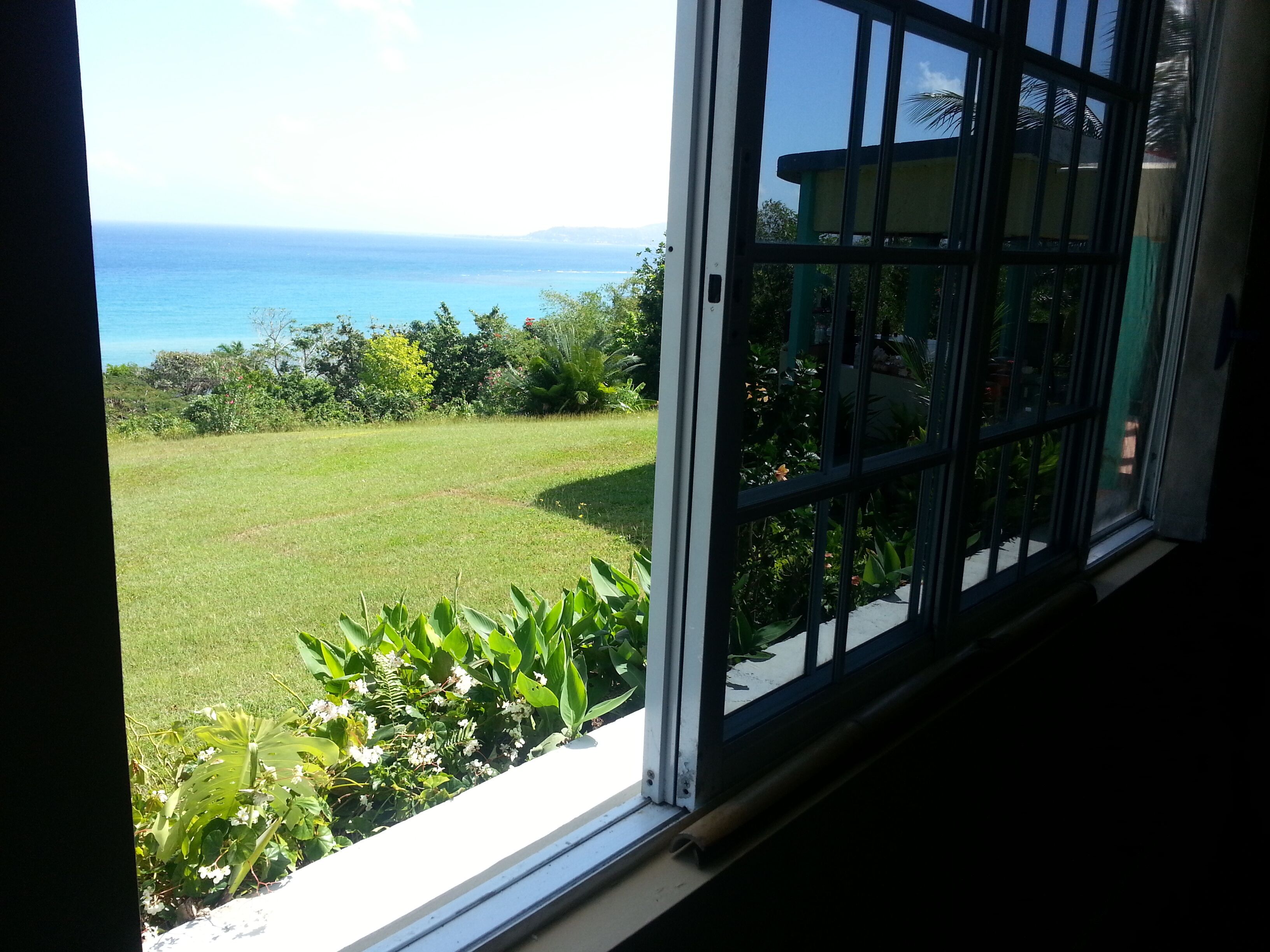 An open window shows the lawn and the sea.