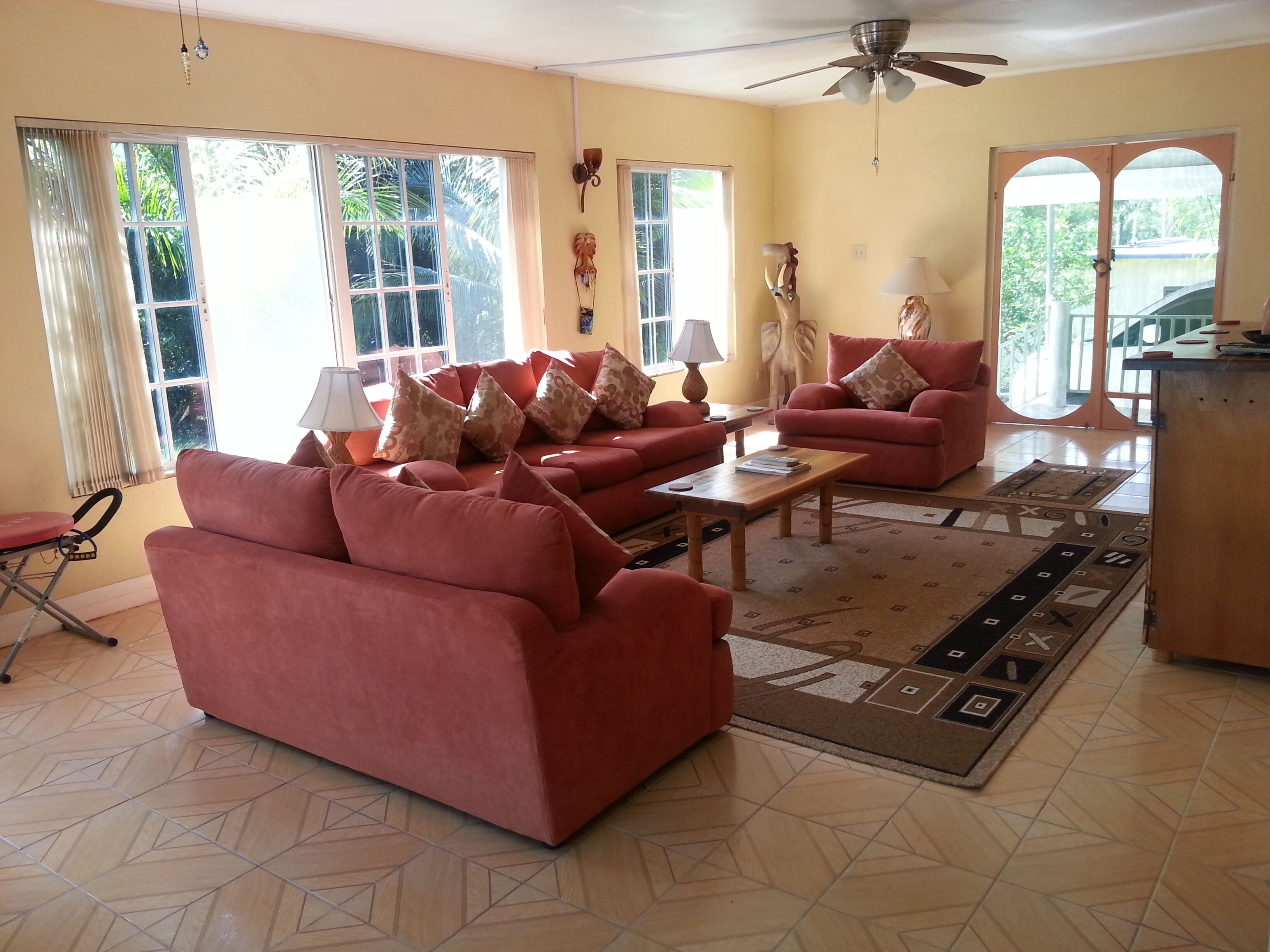 A living room with red sofas, a coffee table, and a ceiling fan.