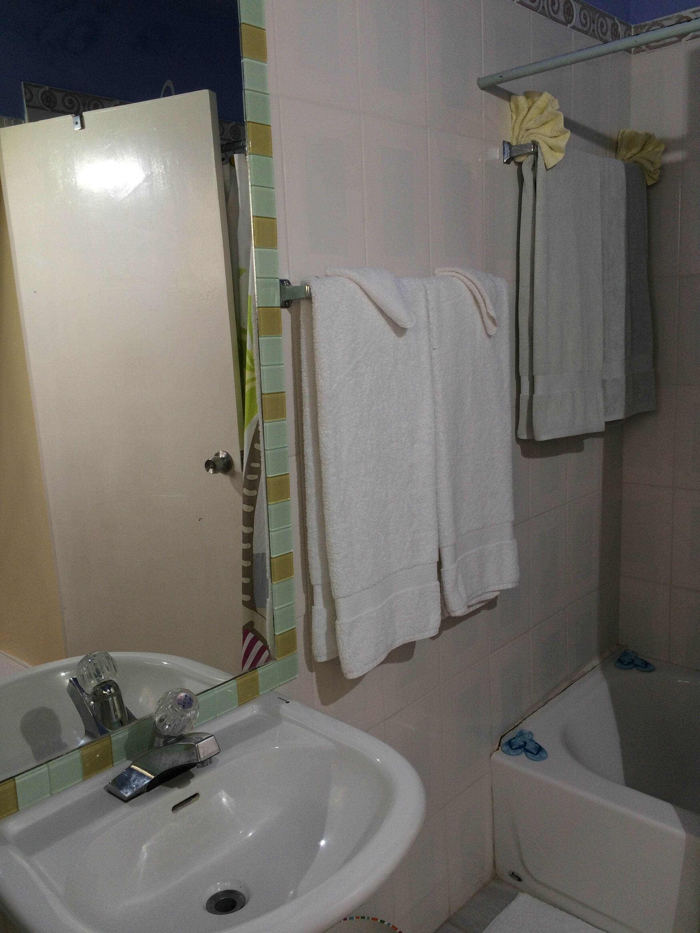 A bathroom with a sink, a mirror, a bathtub, and towels.