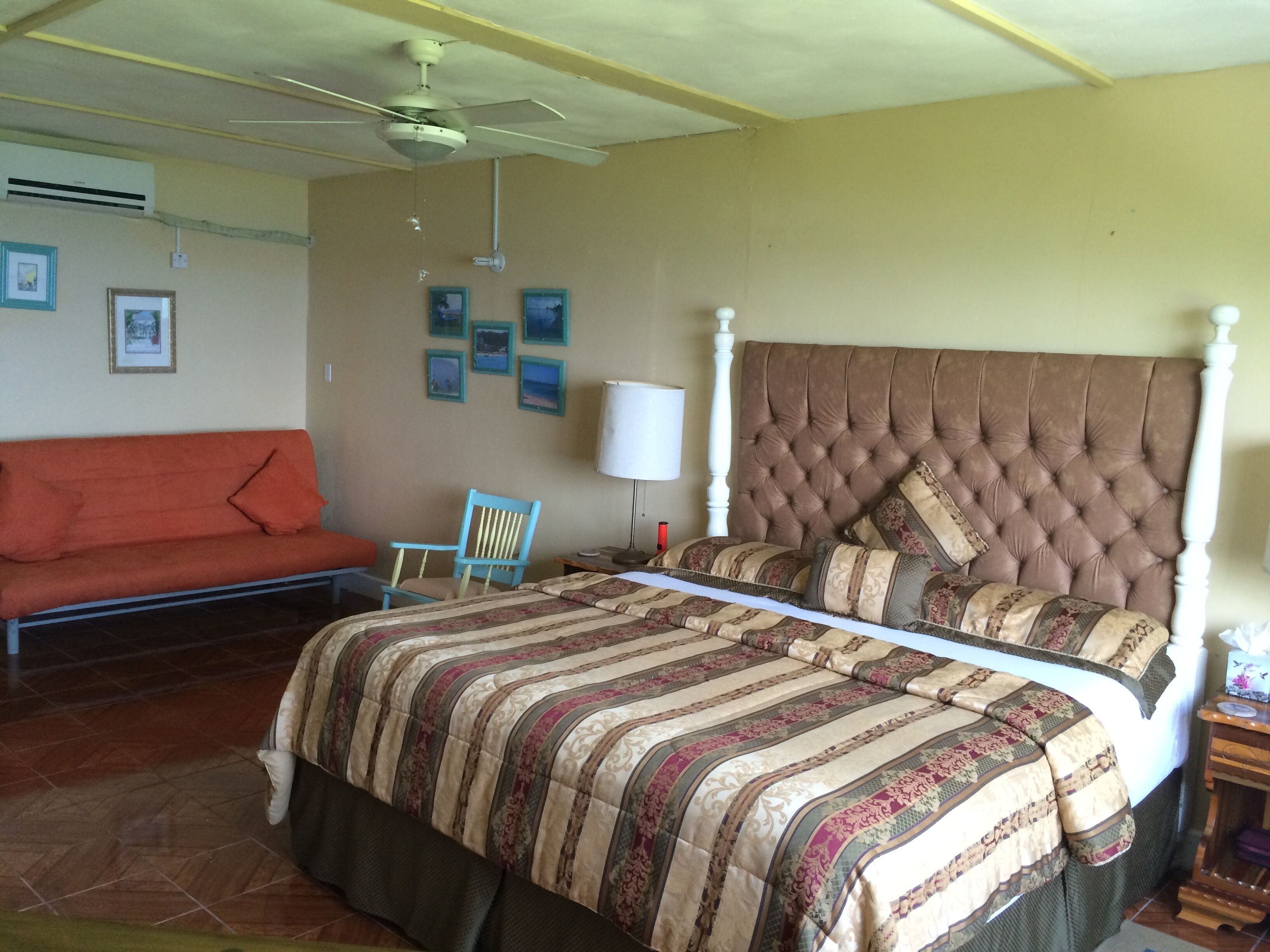 A bedroom with a king bed, a futon, and a ceiling fan.