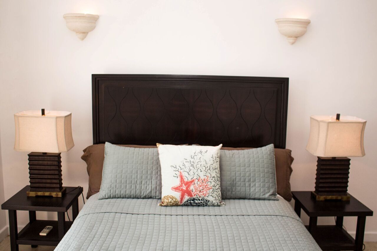 A bedroom with a dark wood headboard and two bedside lamps.